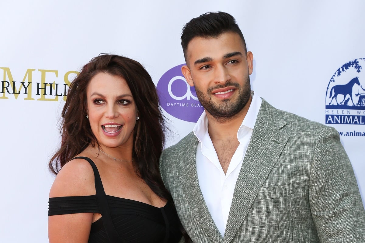 Britney Spears in a black dress and Sam Asghari in a gray suit.