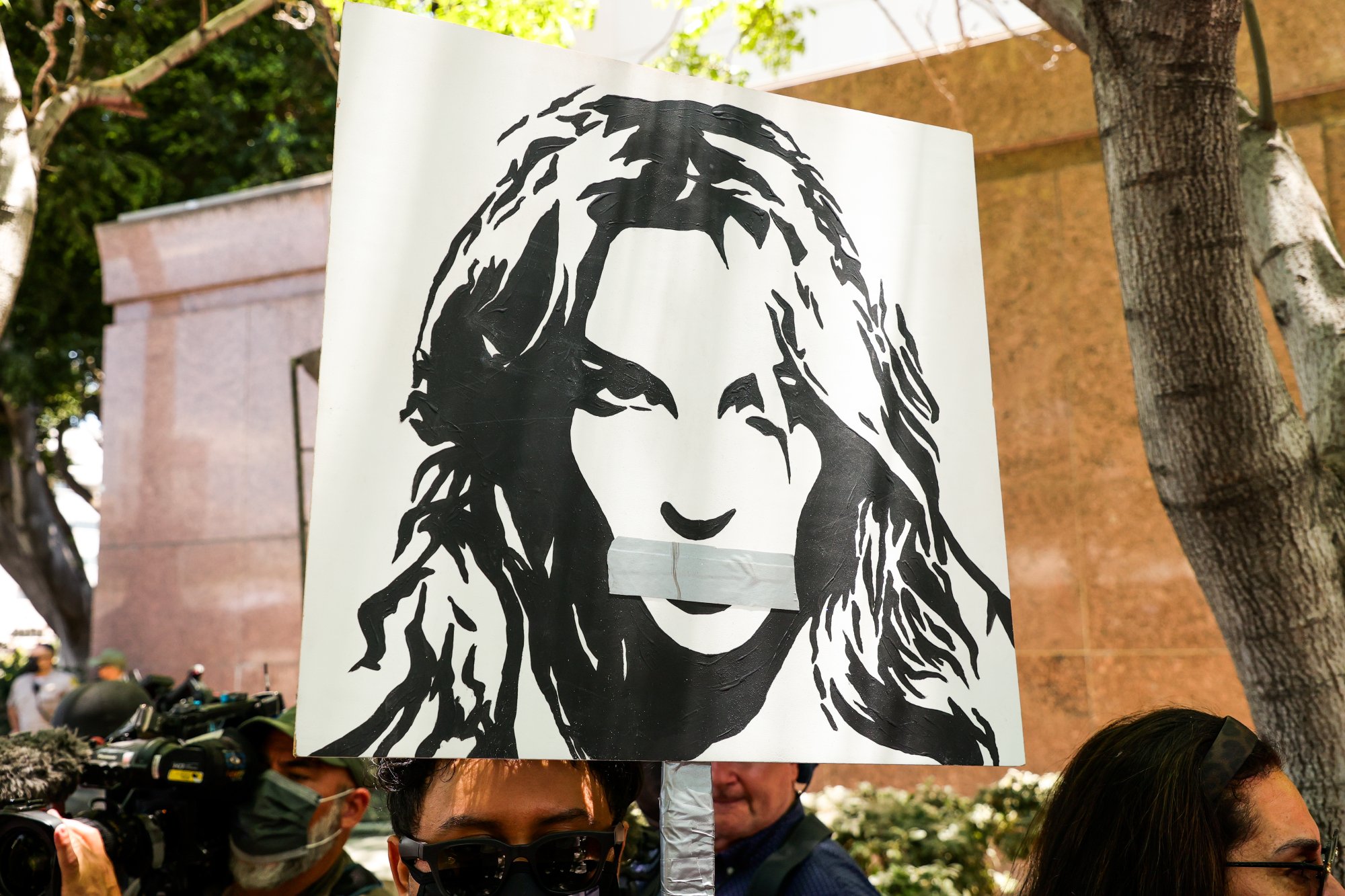 'Britney vs. Spears' #FreeBritney activists protesting during a conservatorship hearing with a poster of Britney Spears with tape over her mouth