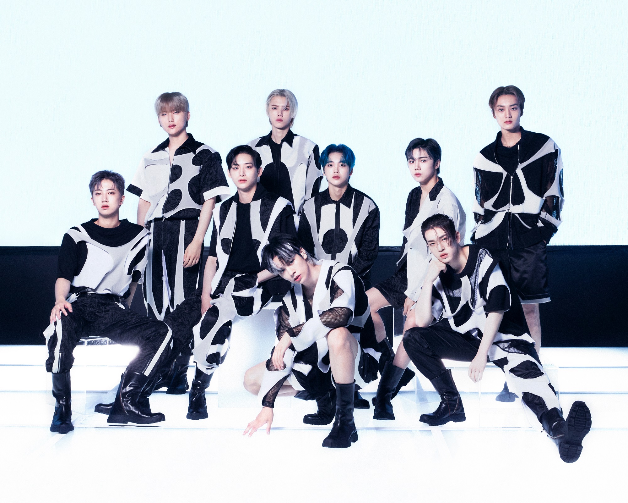 The members of CRAVITY pose in black-and-white outfits for a promotional photo