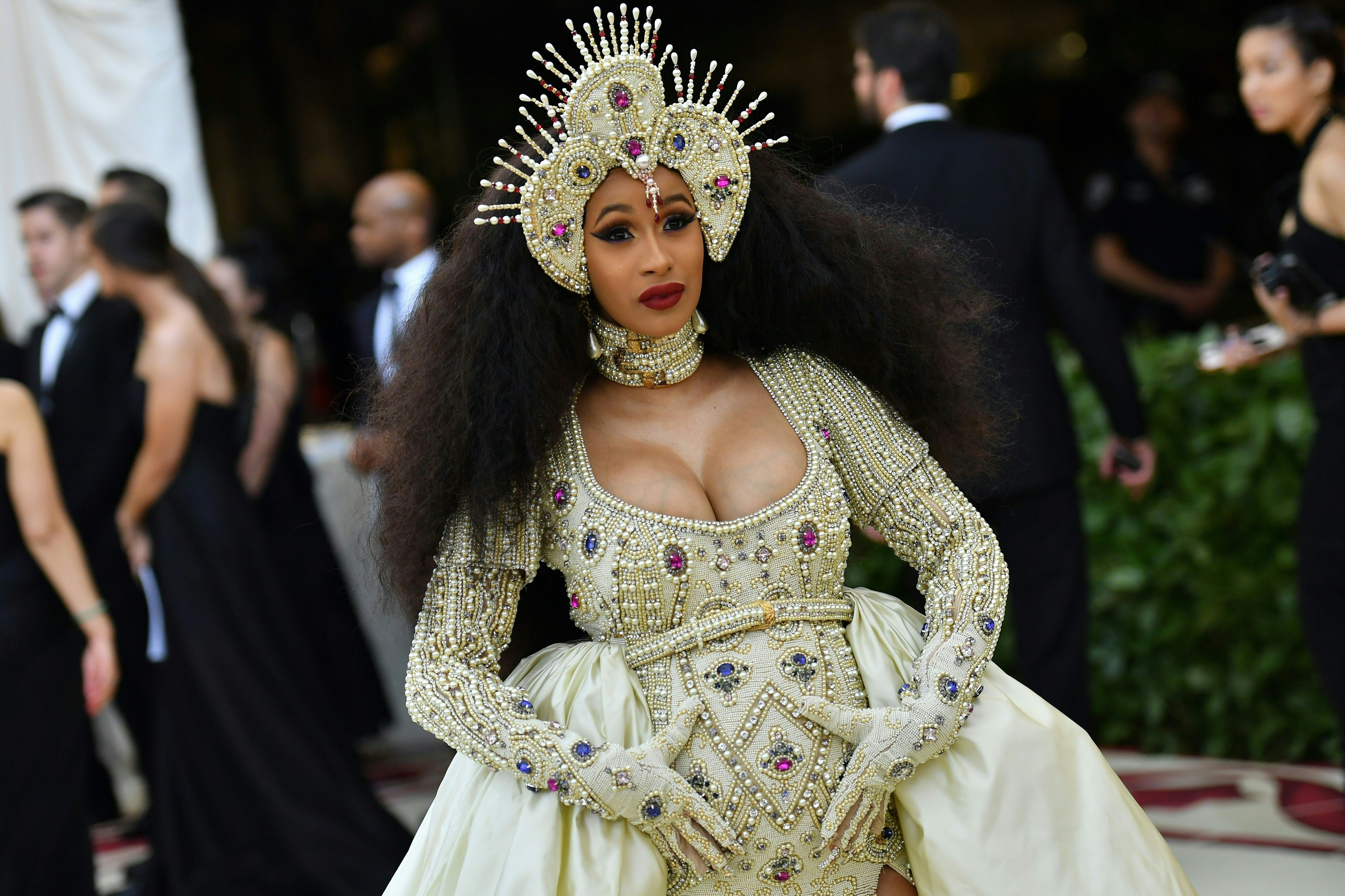 Cardi B holding her baby bump while posing for the camera.