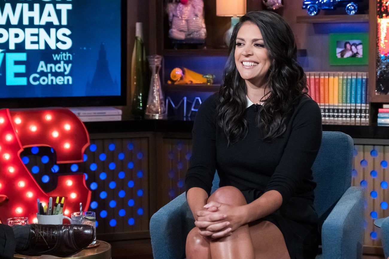 Cecily Strong sitting on a blue chair in a black outfit