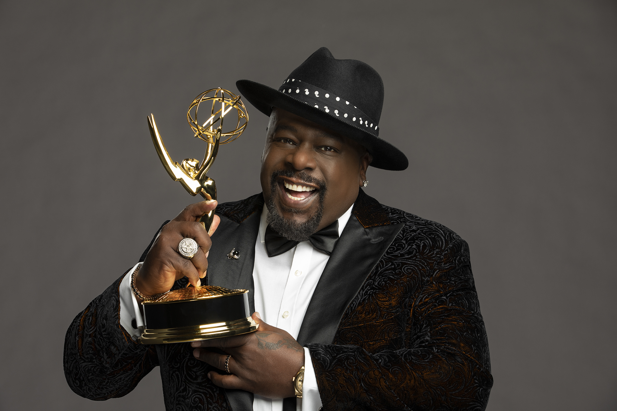 Cedric the Entertainer, the host of the 73rd Primetime Emmy Awards in 2021, smiling and holding an Emmy in his hands