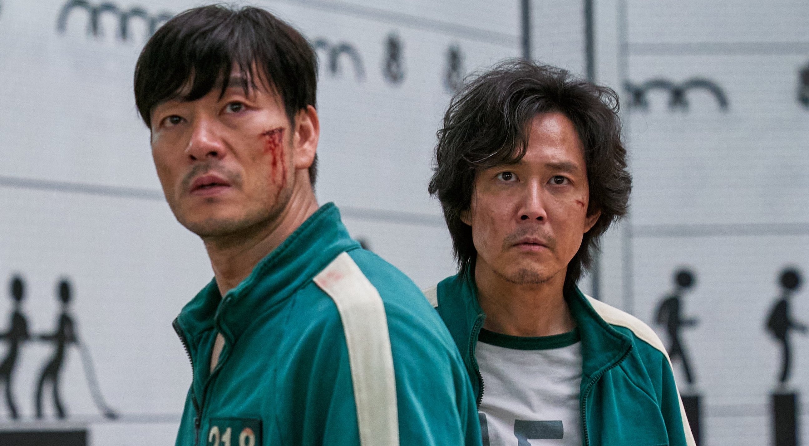 Characters Gi-Hun and Sang-Woo for Netflix's 'Squid Game' wearing green tracksuits with wounded face