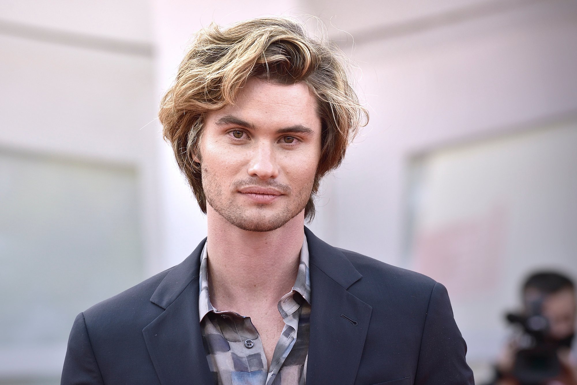 Chase Stokes smiling in front of a blurred background