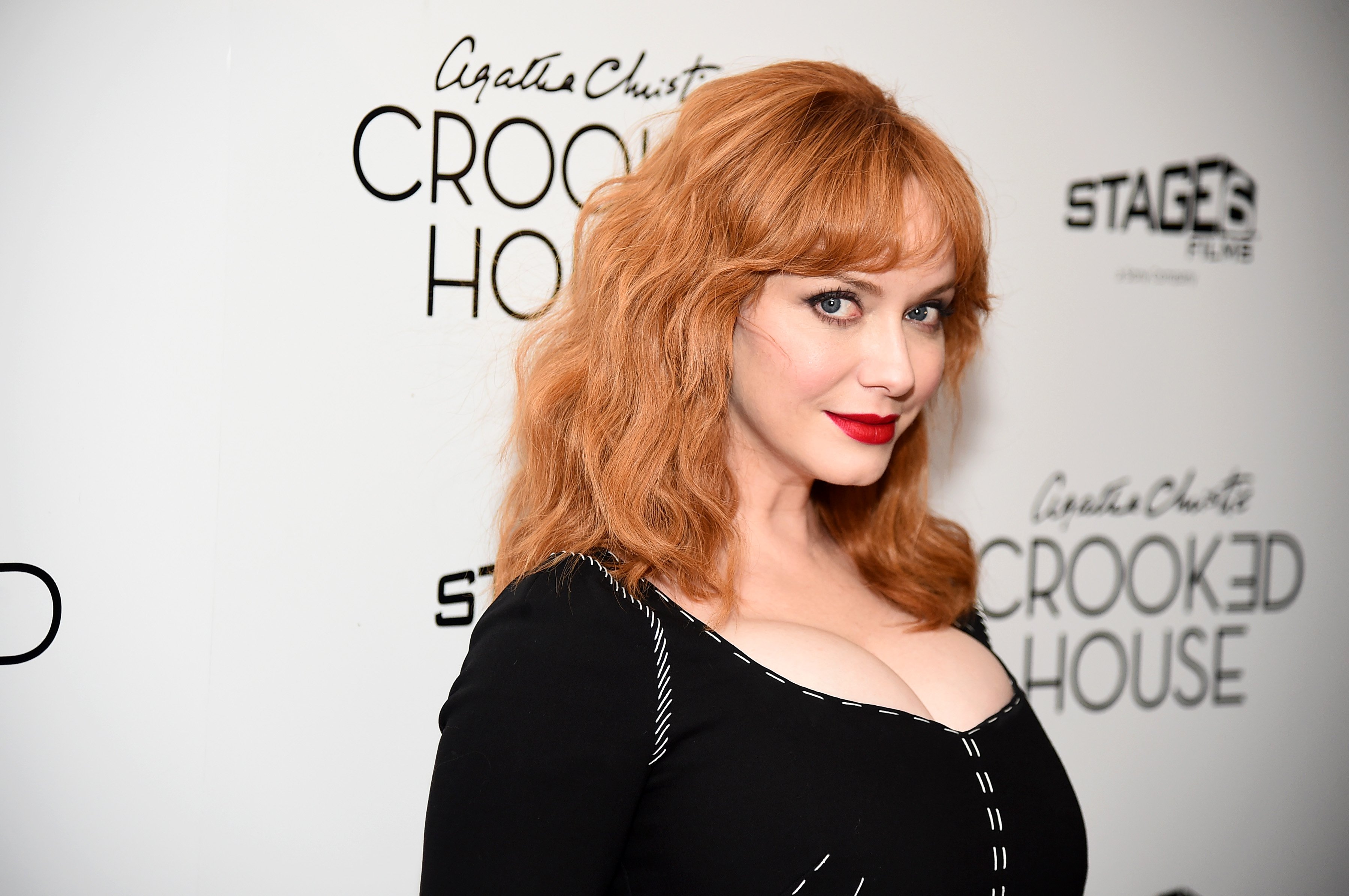 Christina Hendricks smirking at the camera on the red carpet.