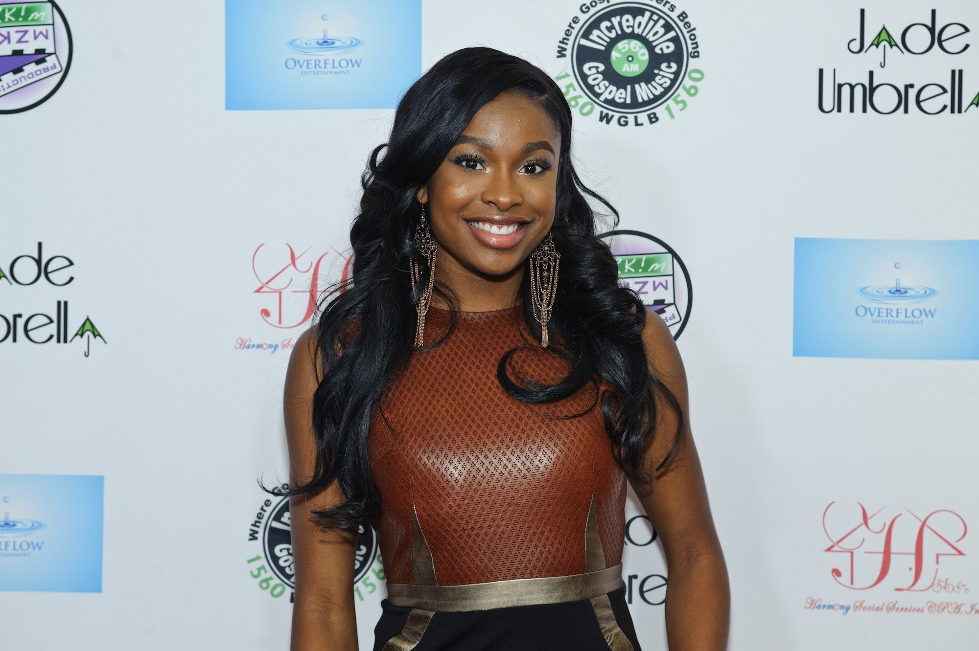 Coco Jones wearing a brown topped dress with gold earrings.