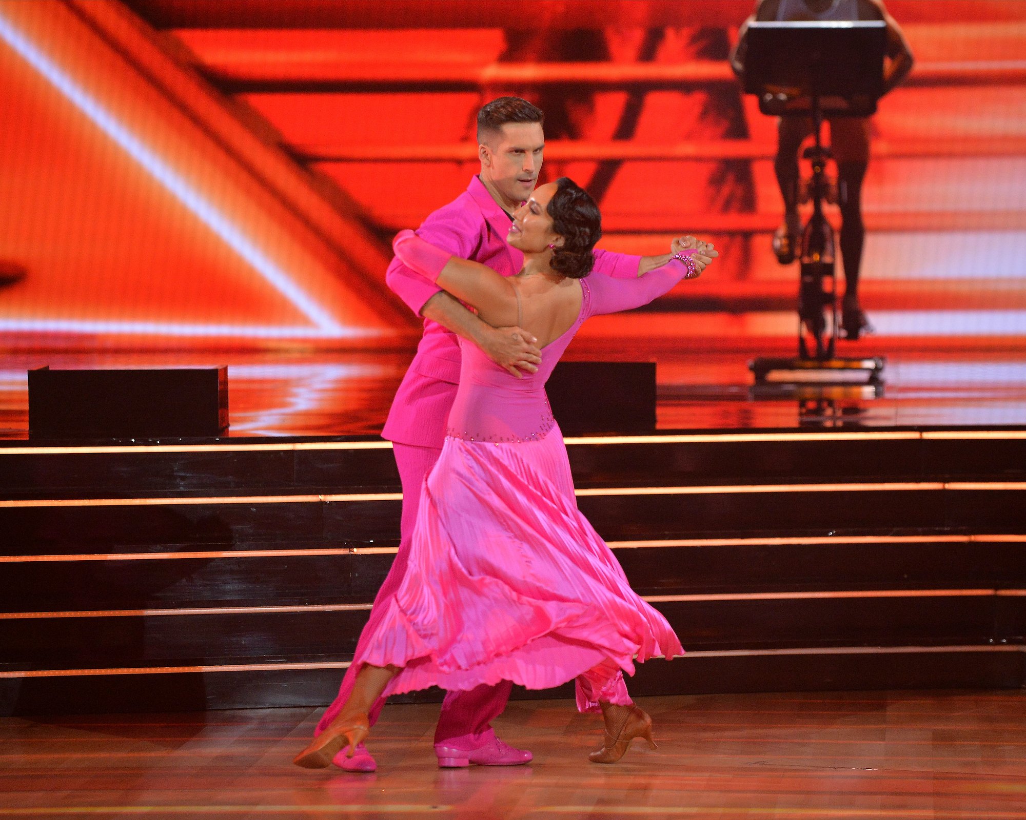 Cody Rigsby wearing a vibrant pink suit dancing a salsa with Cheryl Burke, who is wearing a hot pink dress, during week 1 of 'Dancing With the Stars' Season 30