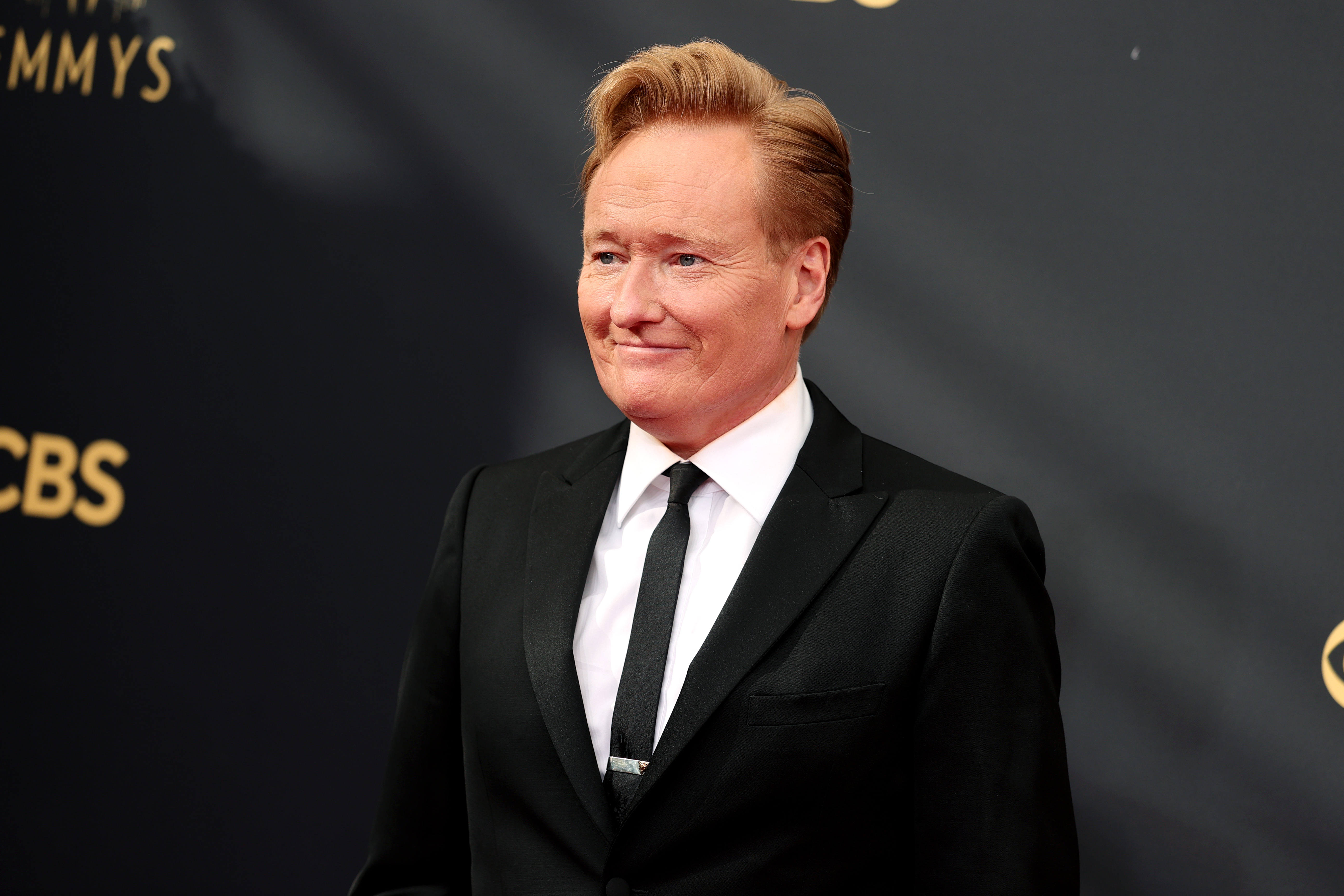 Conan O'Brien attends the 2021 Emmy Awards  in a black suit.