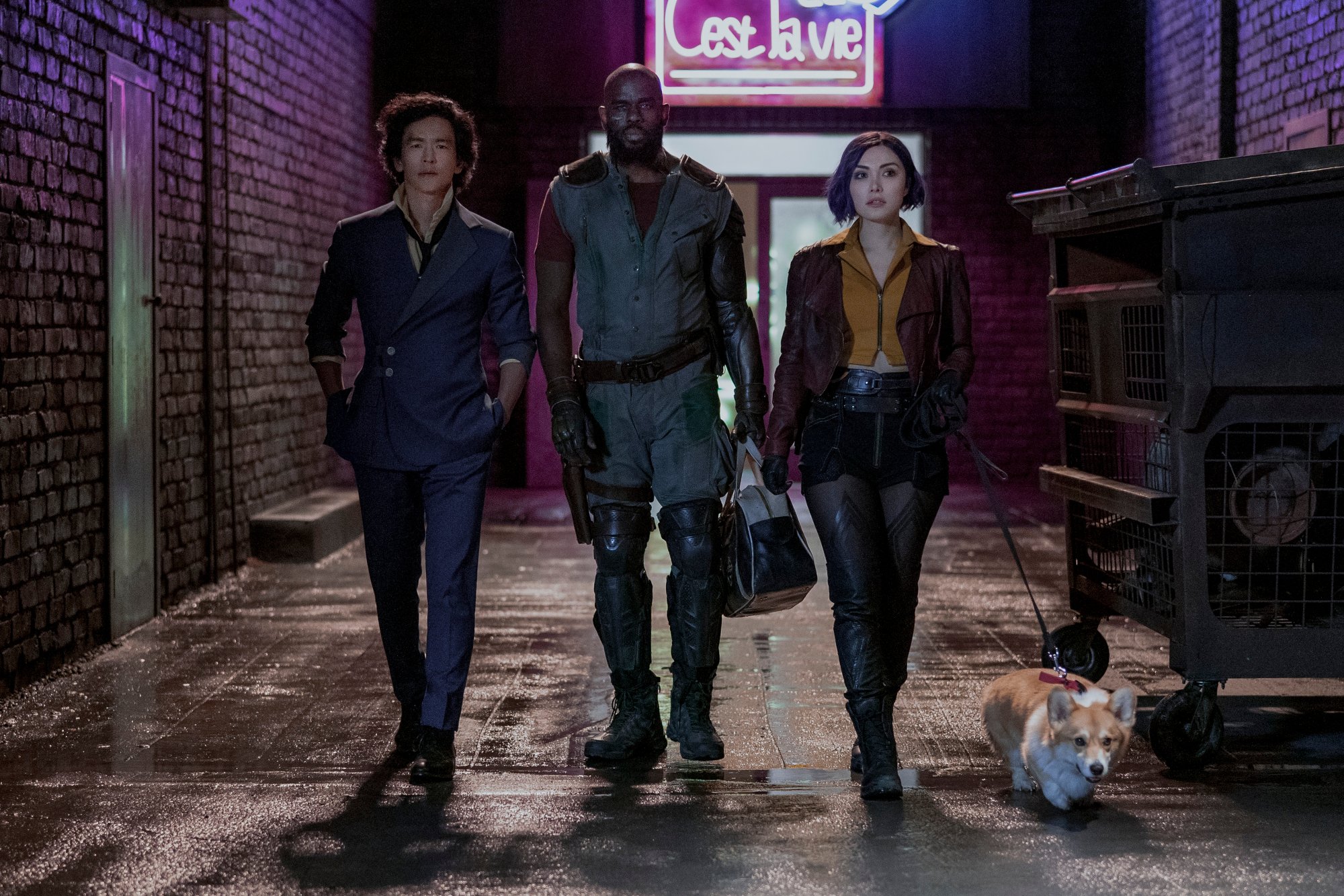 Cast members John Cho, Mustafa Shakir, and Daniella Pineda in Netflix's live-action 'Cowboy Bebop.' The three are walking next to one another, with Ein the corgi/alien next to them. Fans are wondering if the 'Cowboy Bebop' adaptation will feature Ed as well.