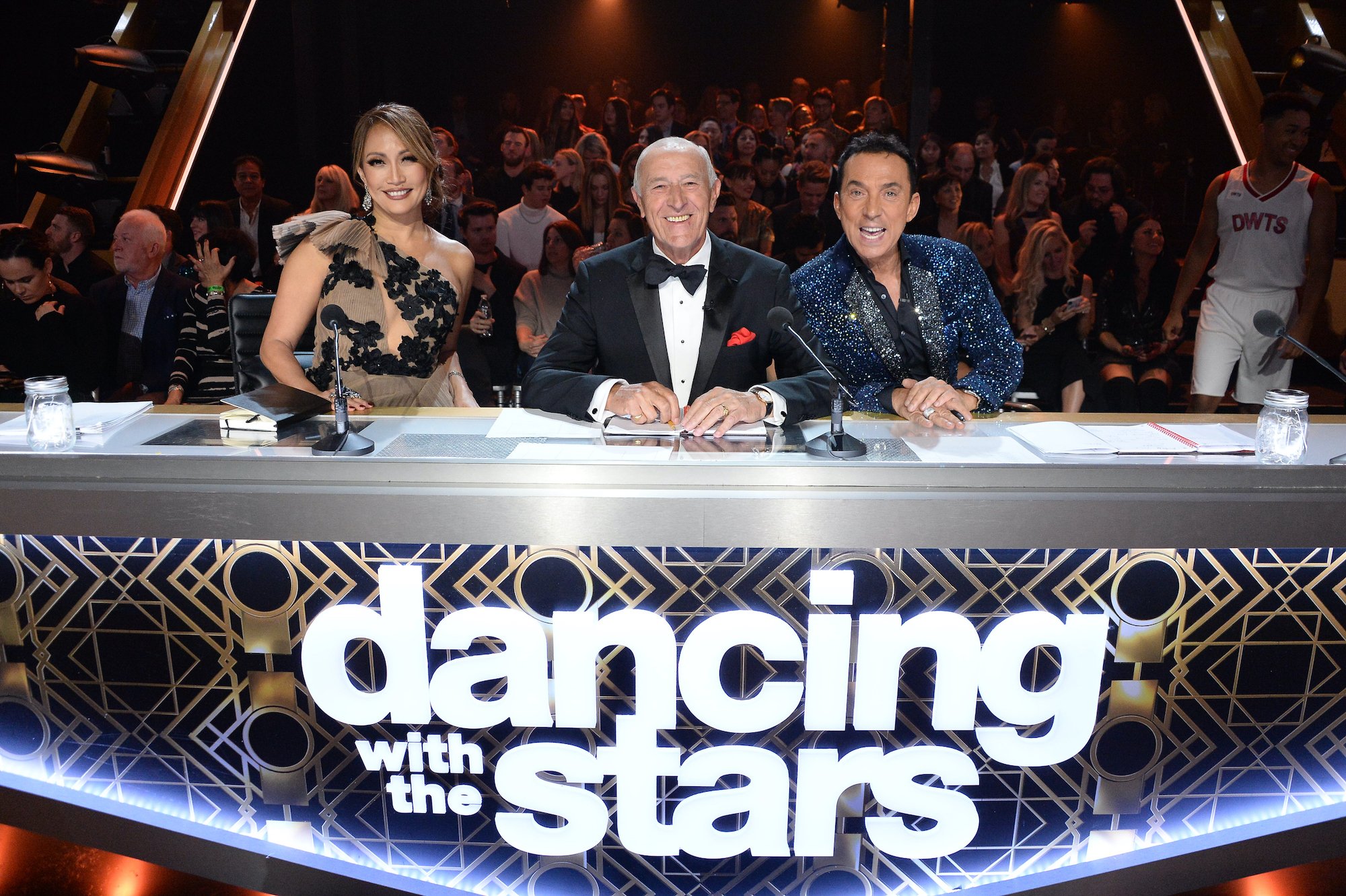 Carrie Ann Inaba, Len Goodman, and Bruno Tonioli sit at the judges table on the set of 'Dancing With the Stars'