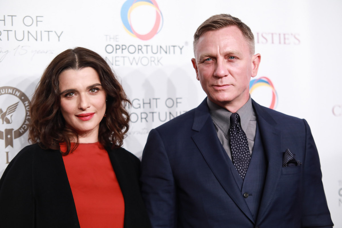 Rachel Weisz and Daniel Craig smiling in front of a white background