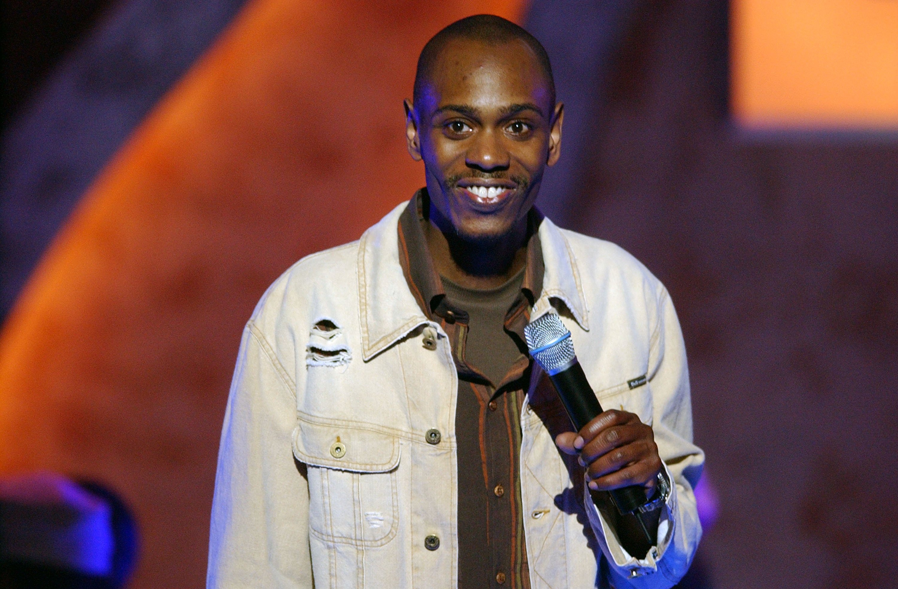 Dave Chappelle in a white jacket onstage in 2003.