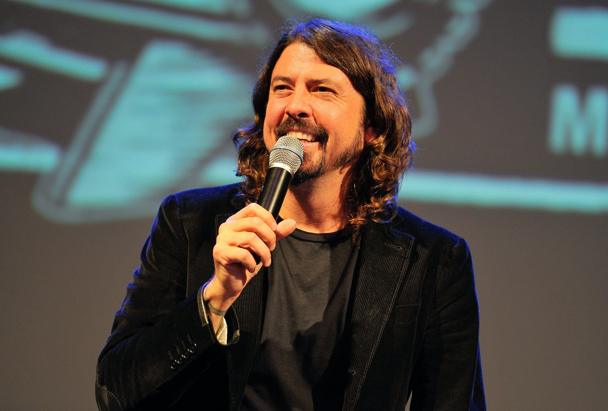 Dave Grohl smiling, holding a microphone