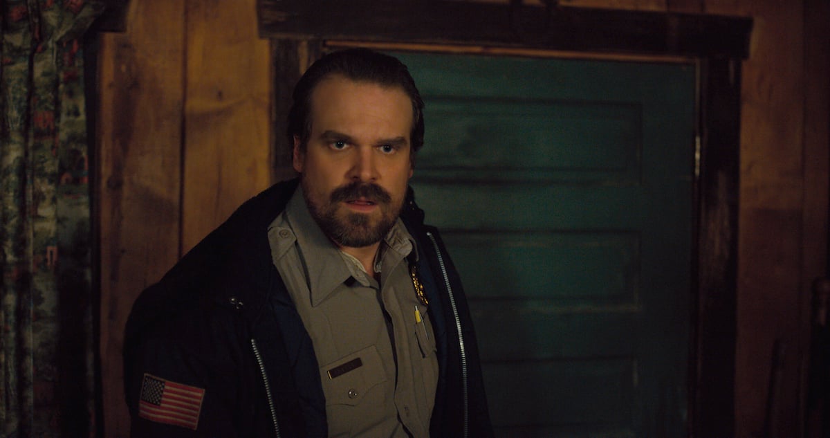 David Harbour in his police uniform looking shocked in a production still from Stranger Things Season 2.