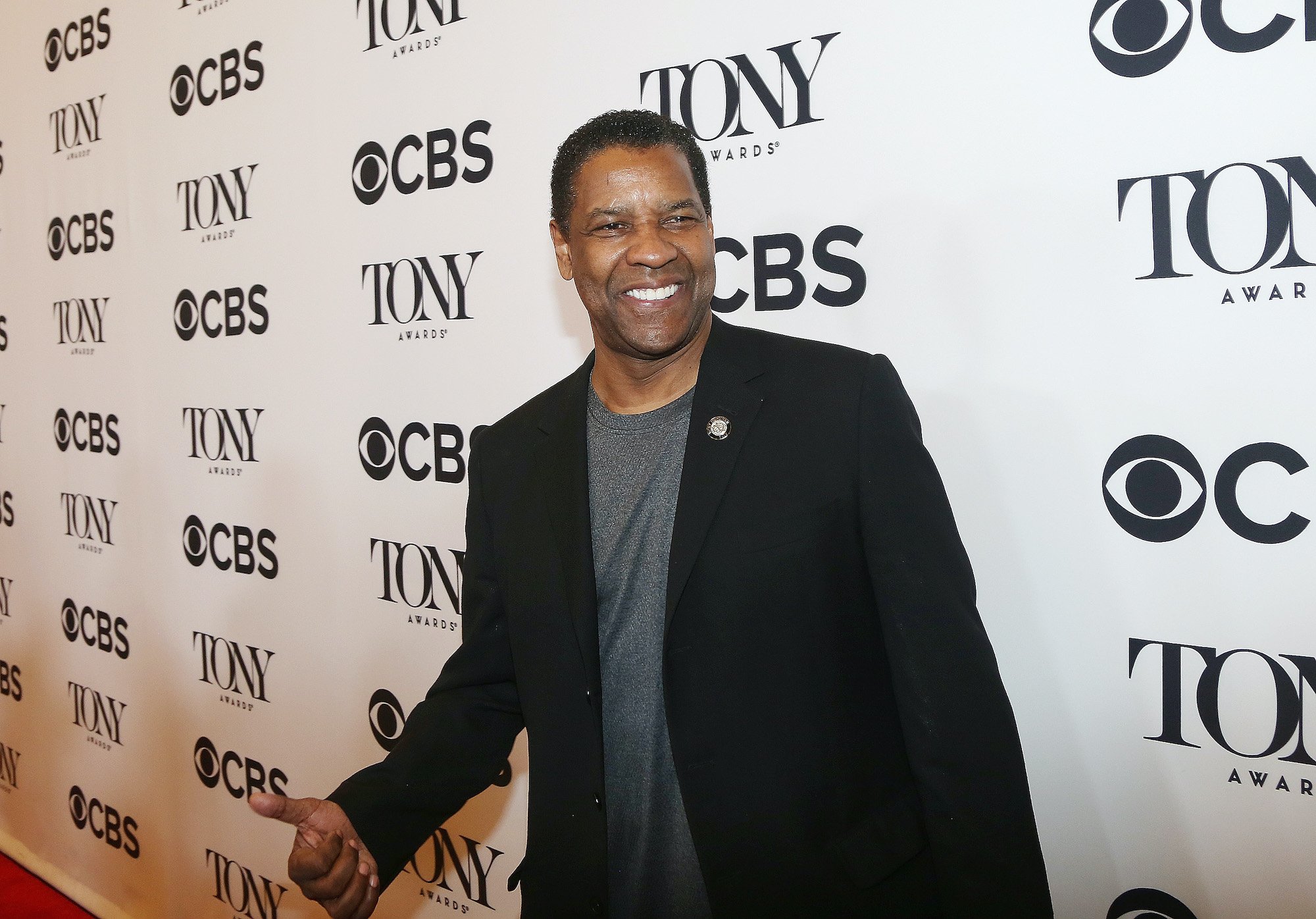 Denzel Washington smiling in front of a white background