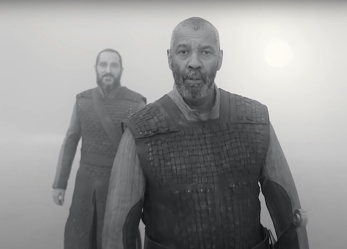 Denzel Washington as Lord Macbeth in 'The Tragedy of Macbeth' trailer. Washington wears traditional Shakespearean garb — a leather piece of armor with a long-sleeved shirt underneath — as he walks through mist with a companion behind him. The photo is in black-and-white. Washington and Frances McDormand co-star in the A24 film, written and directed by Joel Coen. The Shakespearean tragedy hits theaters Dec. 25 and Apple TV+ Jan. 14.