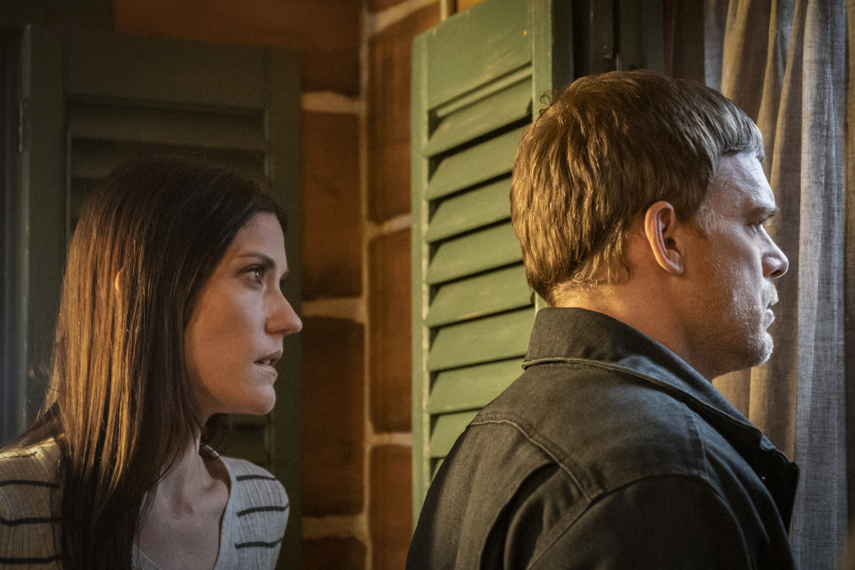 'Dexter: New Blood' Star Michael C. Hall looks out the window wearing a brown jacket and Jennifer Carpenter stands behind him wearing a striped top.