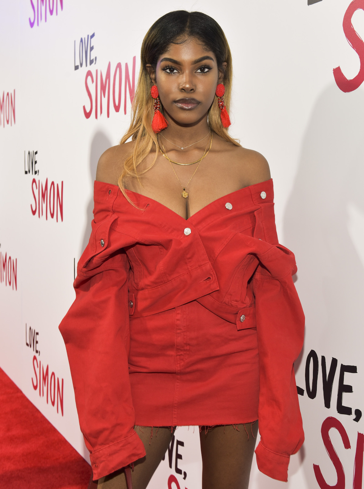 Diamond white wears an off-shoulder red dress at an event.