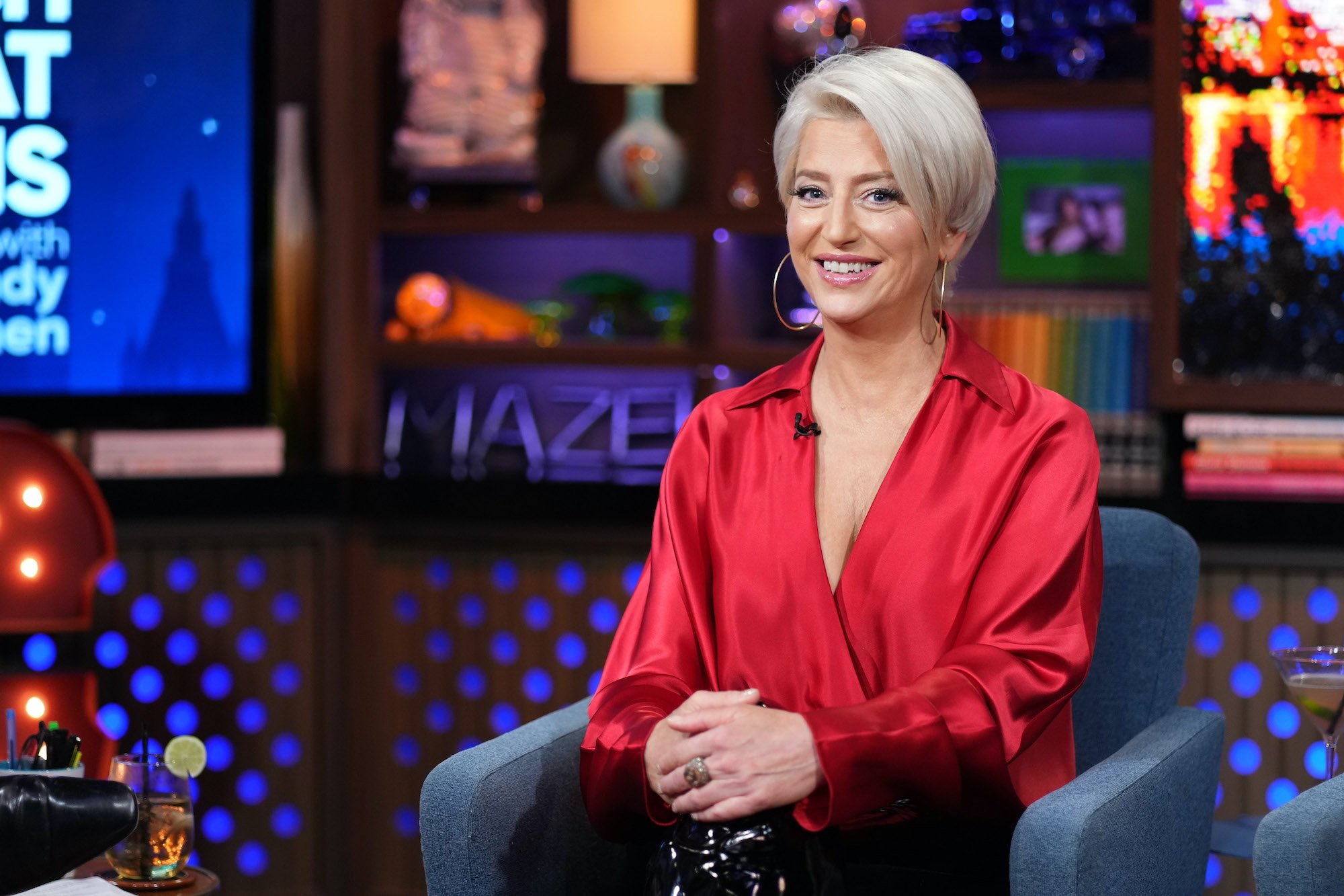 Dorinda Medley smiling, seated in front of bookshelves