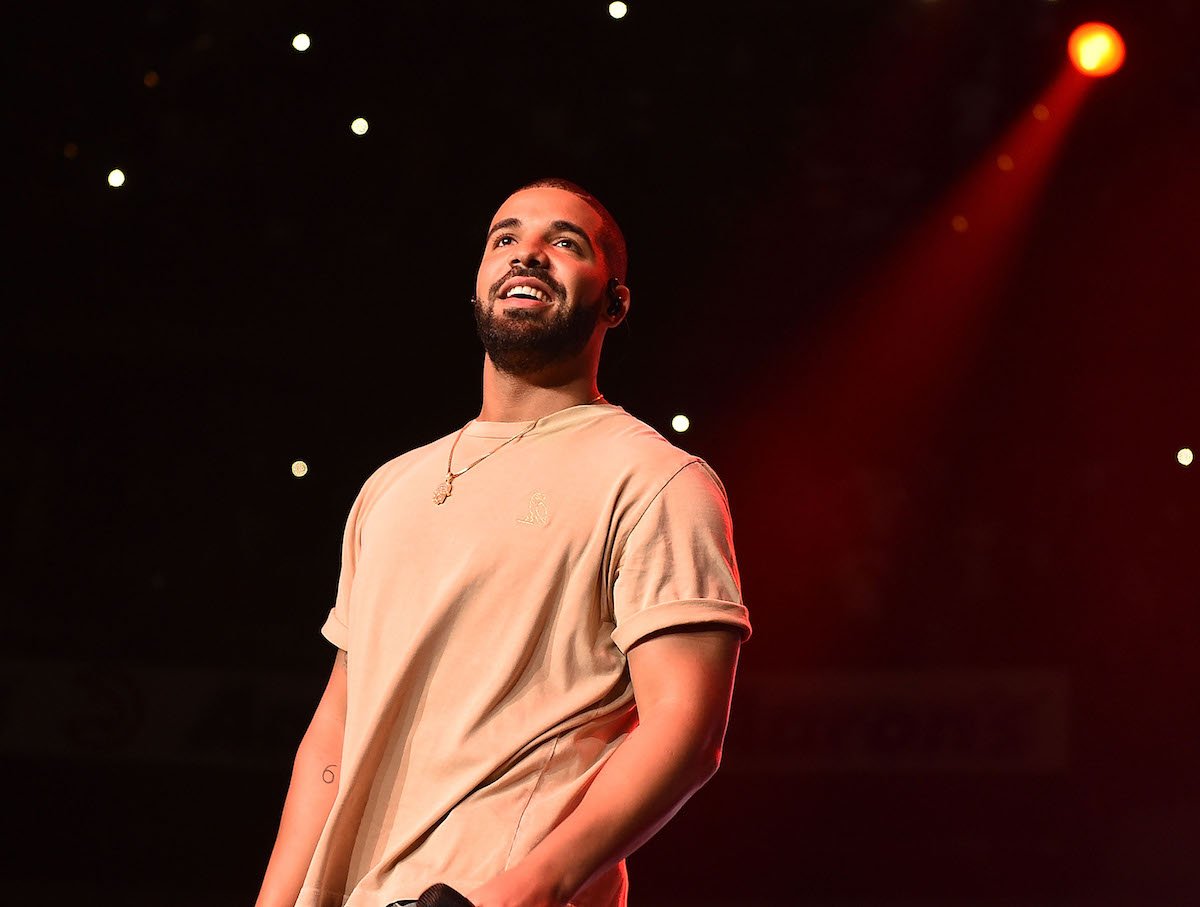 Drake smiles while wearing a tan shirt on stage at the Phillips Arena on June 20, 2015 in Atlanta, Georgia.