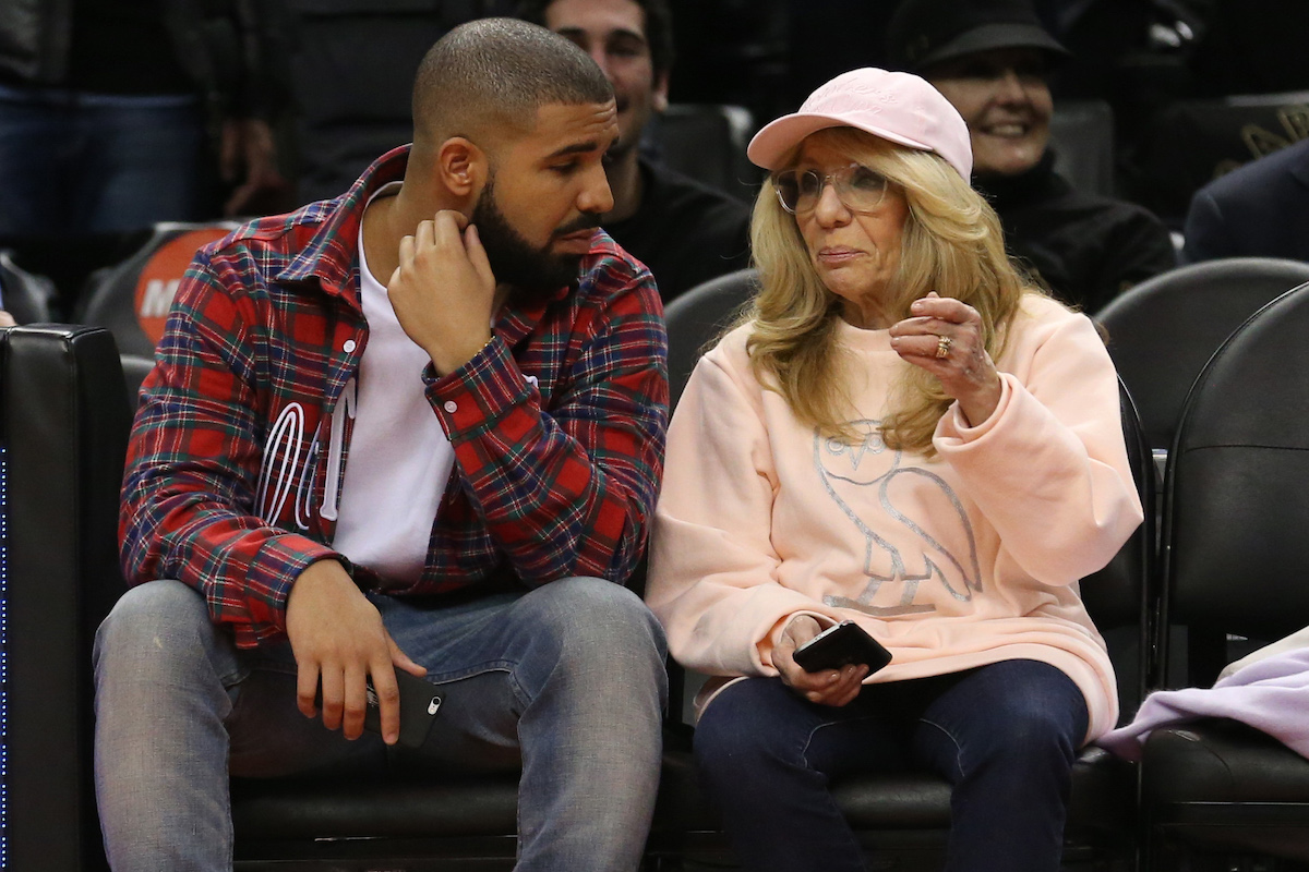 Drake and Sandi Graham sit court side in a red and grey plaid shirt and a blush ovo sweat shirt at the Toronto Raptors vs Cleveland Cavaliers game.