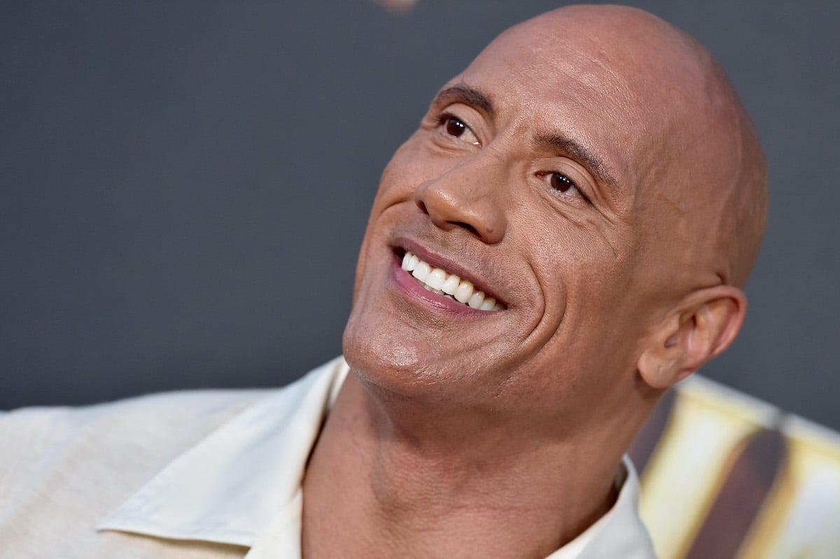 Dwayne Johnson smiling in front of a dark background