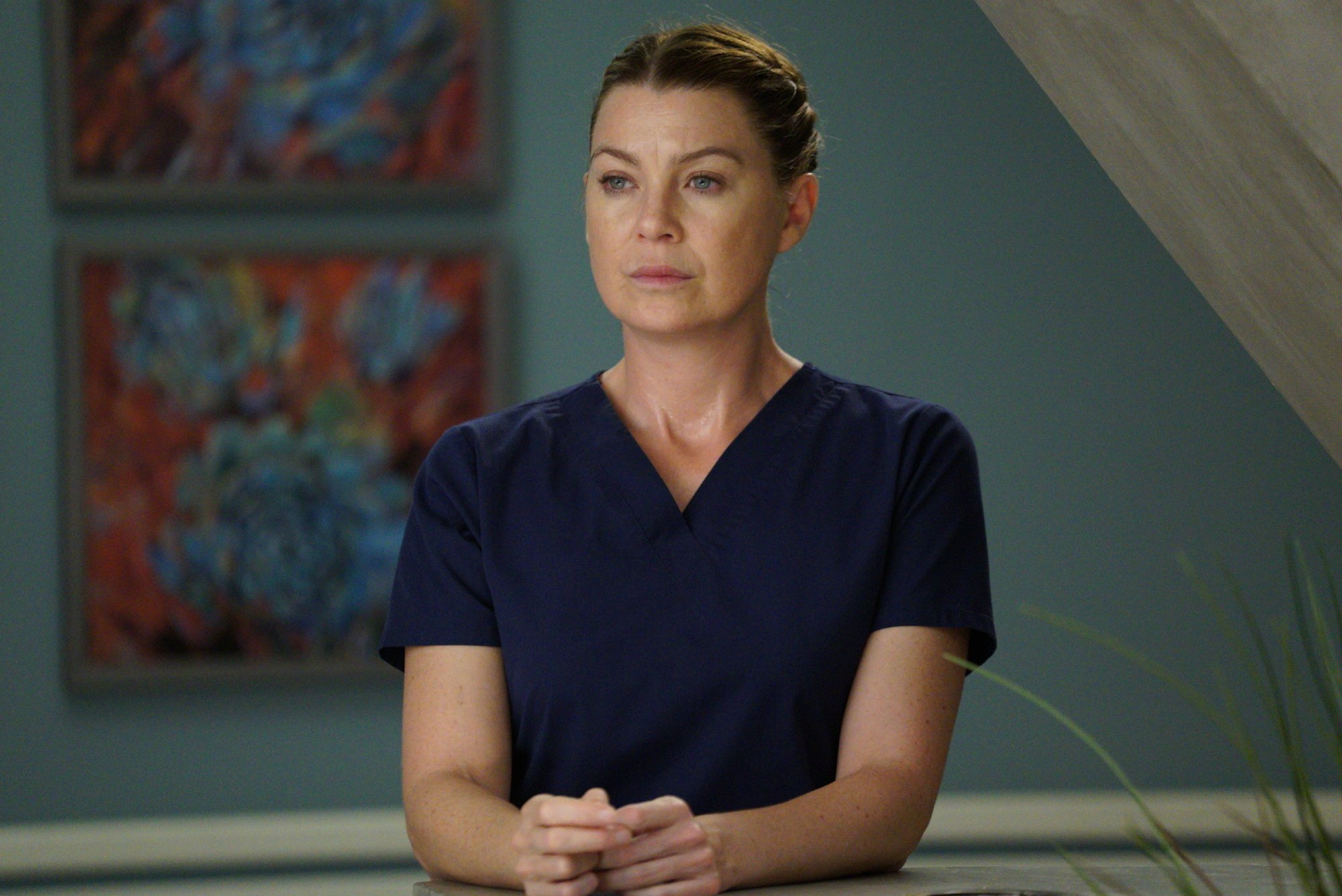 Ellen Pompeo standing in blue scrubs in 'Grey's Anatomy' Season 14.