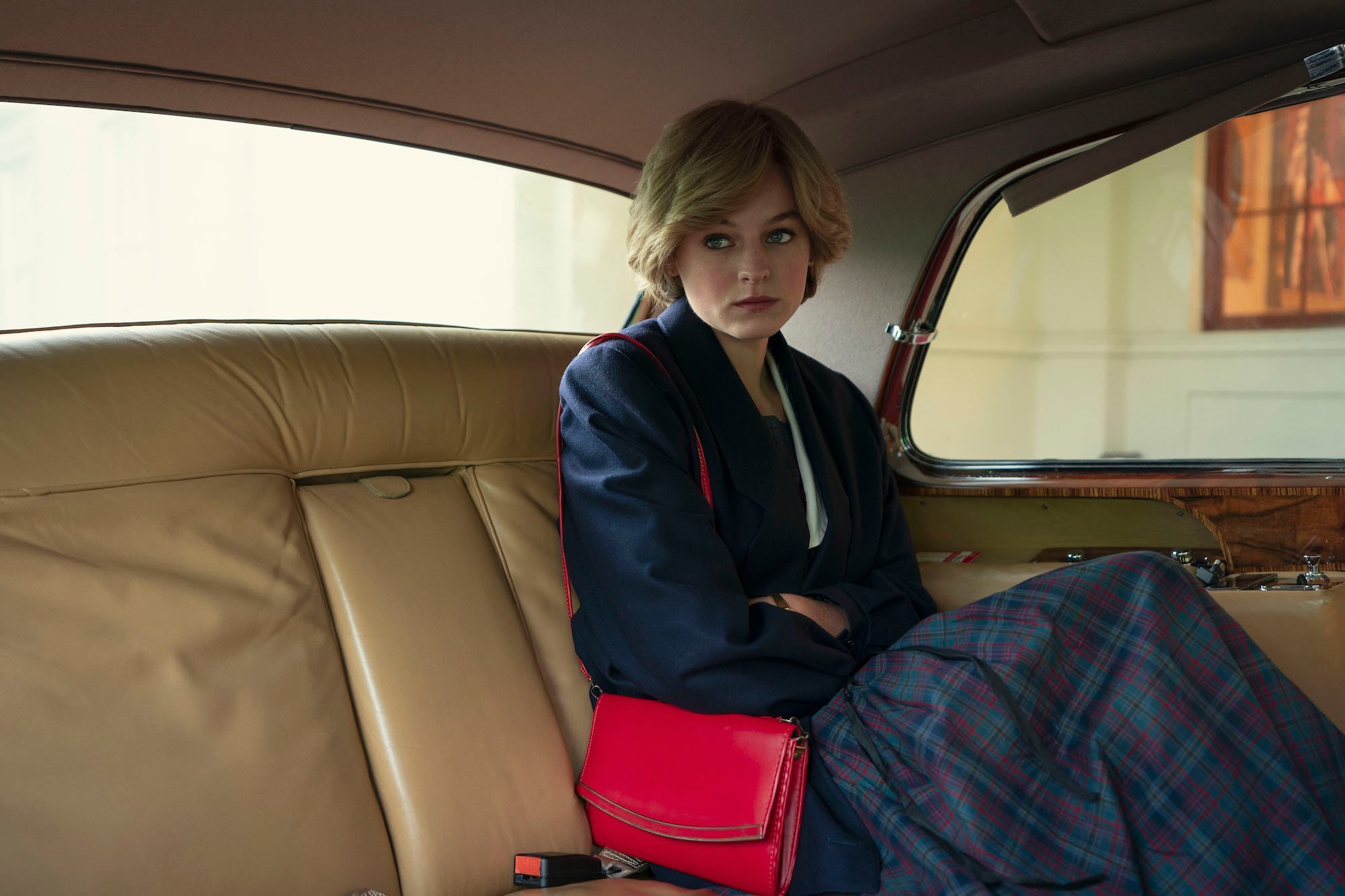 Emma Corrin as Princess Diana sitting in the back of a car in 'The Crown.'