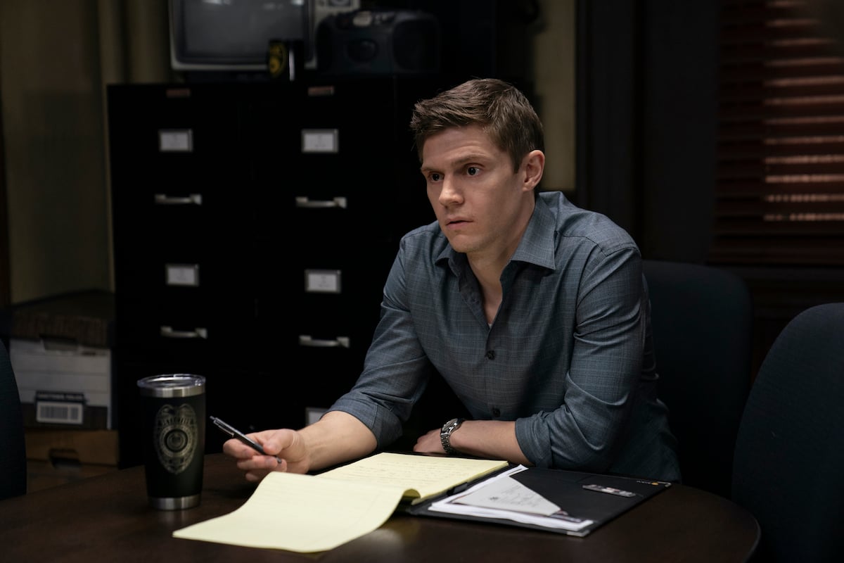 Evan Peters sitting at a desk with a paper notebook in 'Mare of Easttown.'