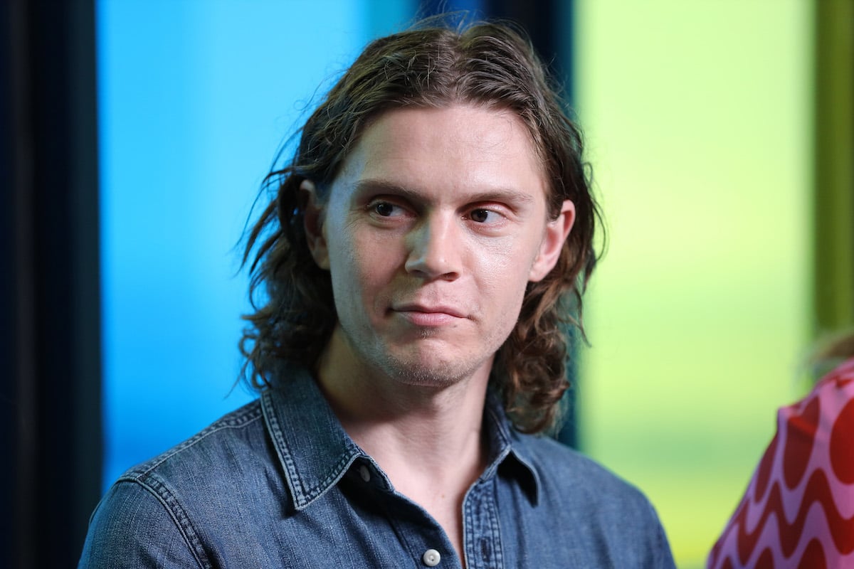 Evan Peters wearing a denim shirt and smirking away from the camera.
