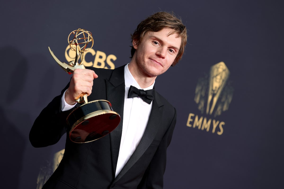 Evan Peters wearing a tuxedo and holding an Emmy Award.