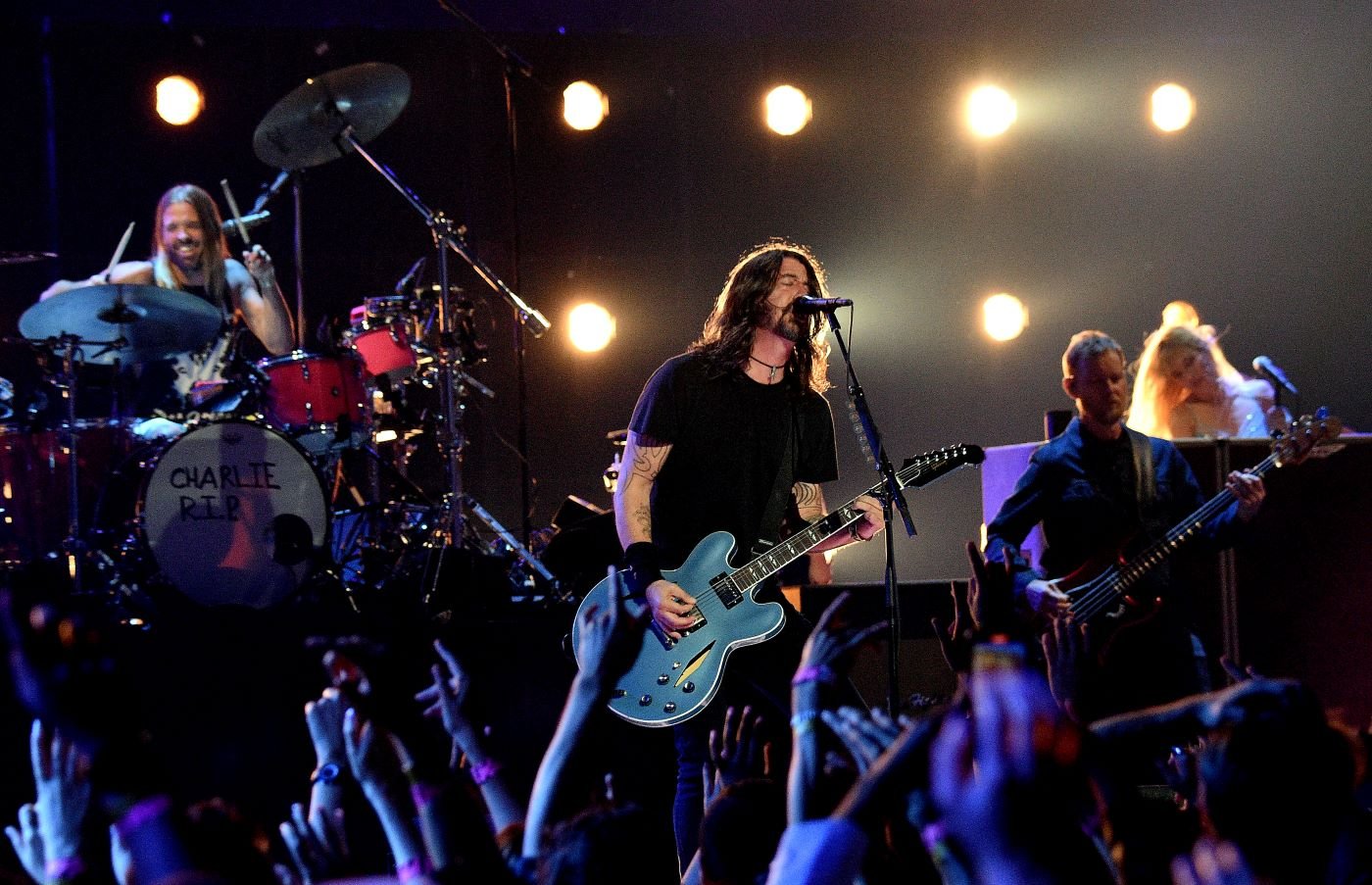 Foo Fighters performing on stage with a background of numerous white lights.