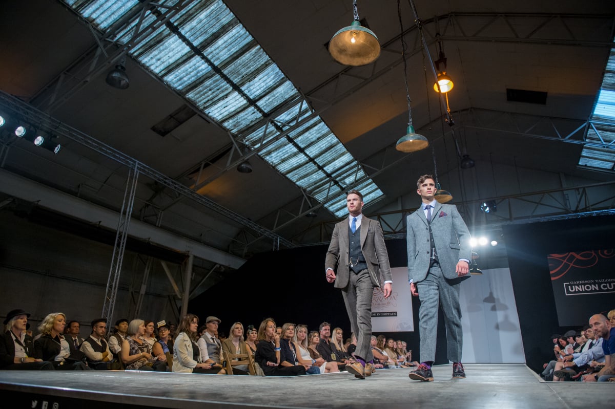 Two men model their 'Peaky Blinders' style three-piece suits at a fashion show.