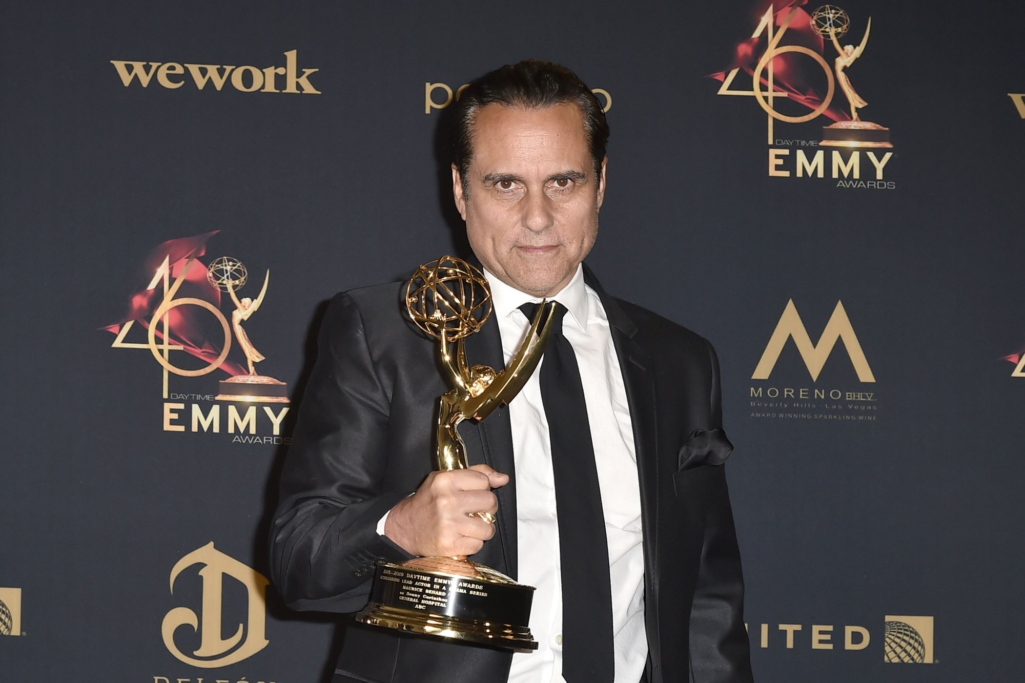 General Hospital star Maurice Benard is pictured here holding a Daytime Emmy while wearing a black suit and a purple collared shirt