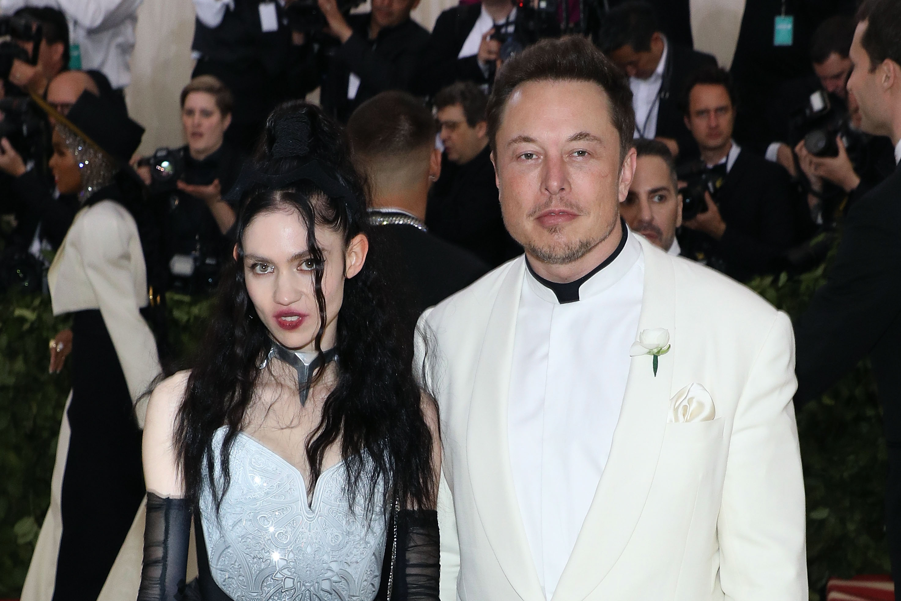 Grimes and Elon Musk, who recently broke up, pose together on the Met Gala red carpet in black and white outfits.