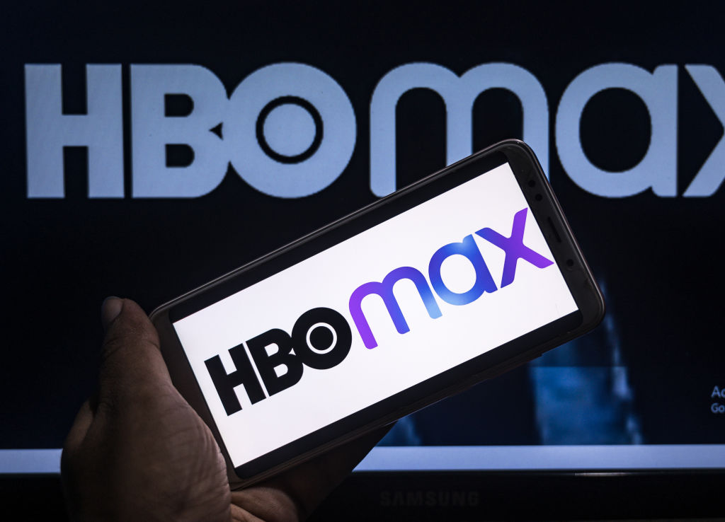 HBO Max logo on a phone screen in front of a poster.