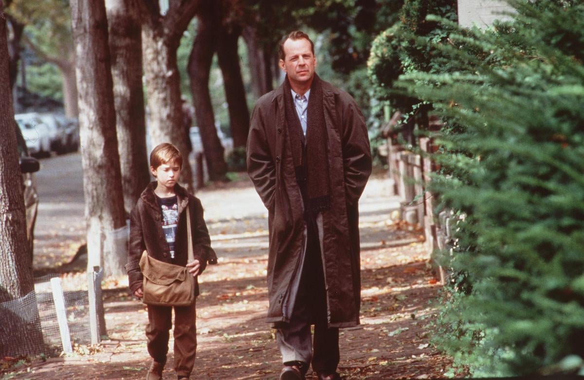 Haley Joel Osment walks down the street next to Bruce Willis in a scene from 'The Sixth Sense'