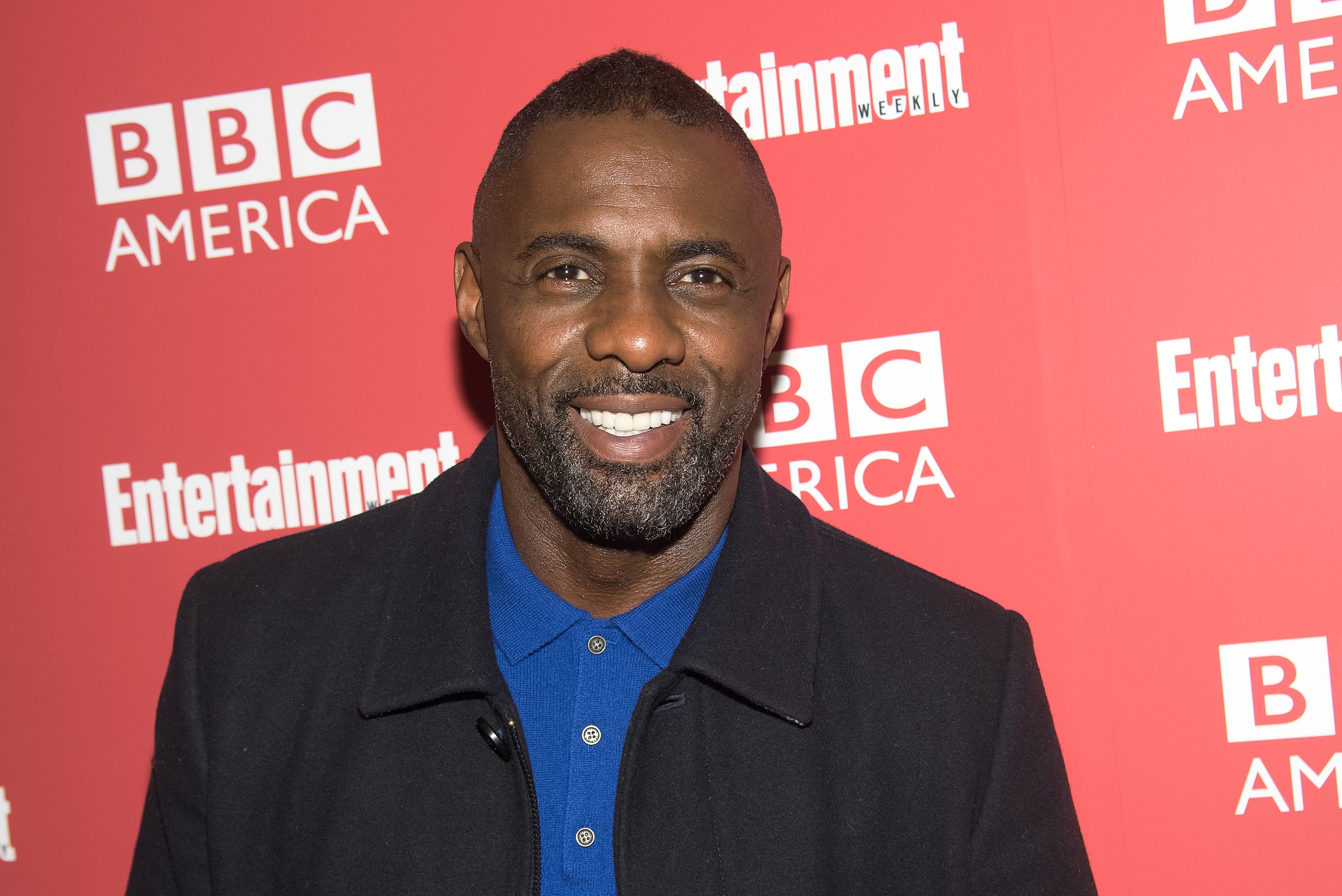 Idris Elba in a blue buttoned t-shirt and black jacket at the screening of his show 'Luther' in 2015.