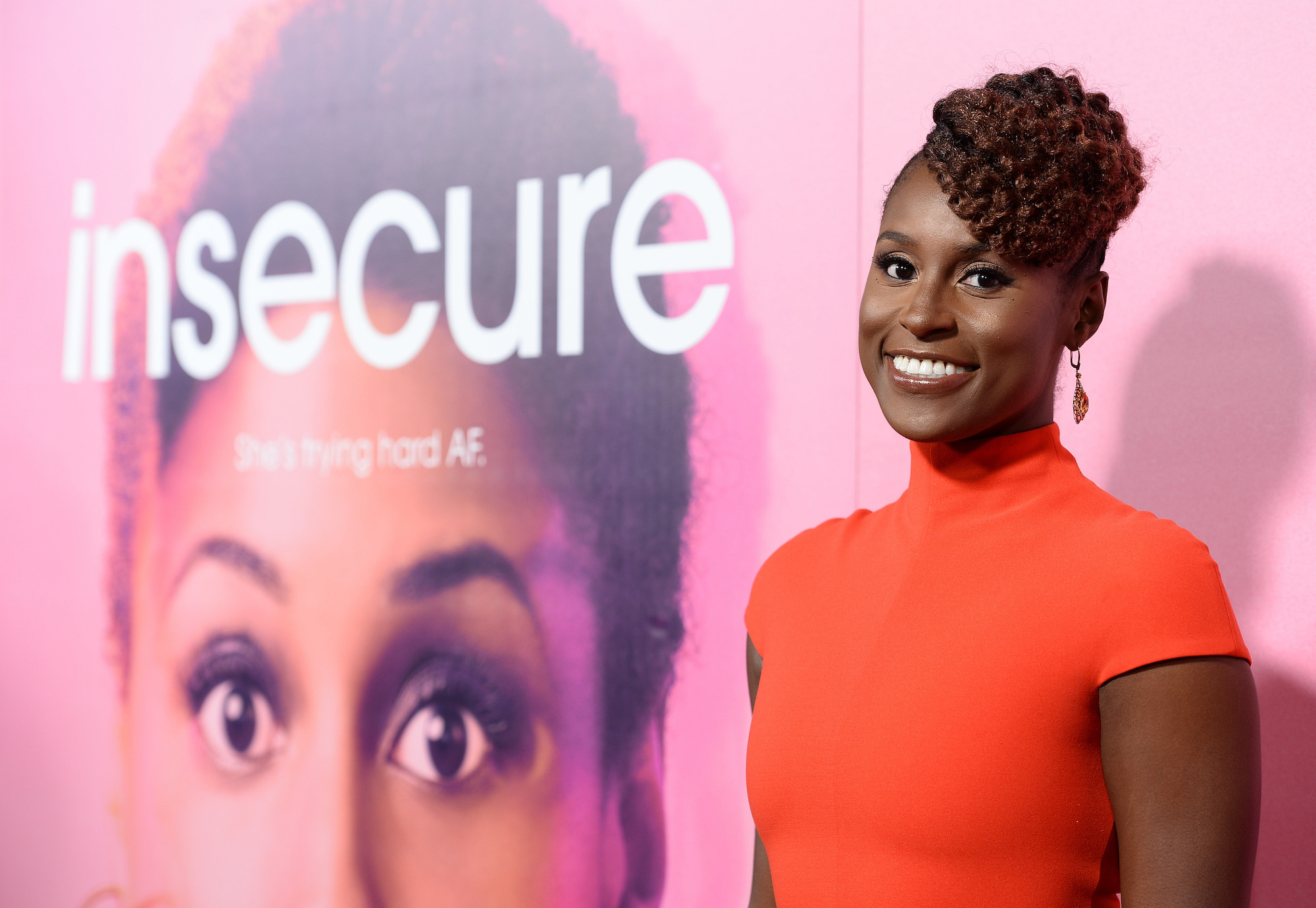 Issa Rae is standing in front of an 'Insecure' poster.