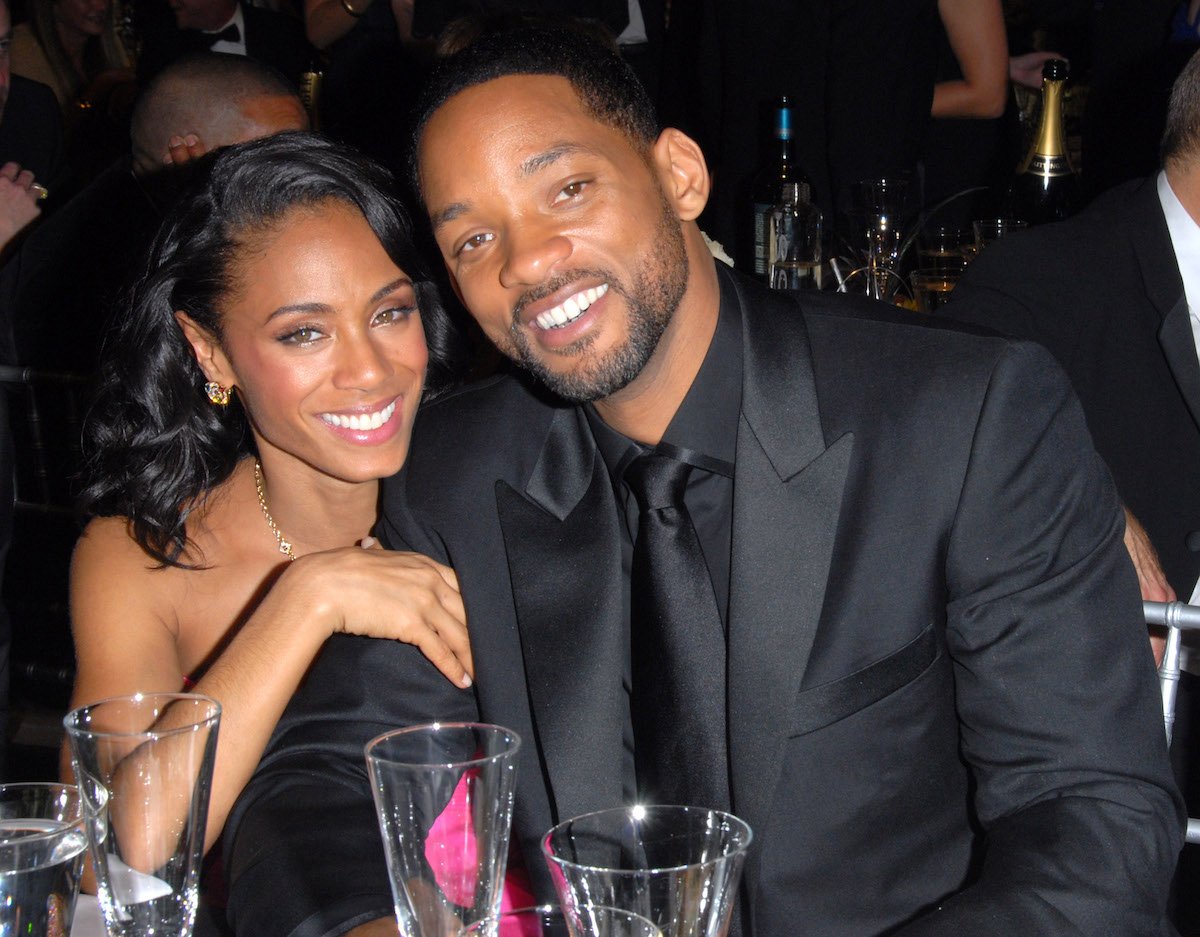 Jada Pinkett Smith and Will Smith smile for the camera in matching black outfits at an event.
