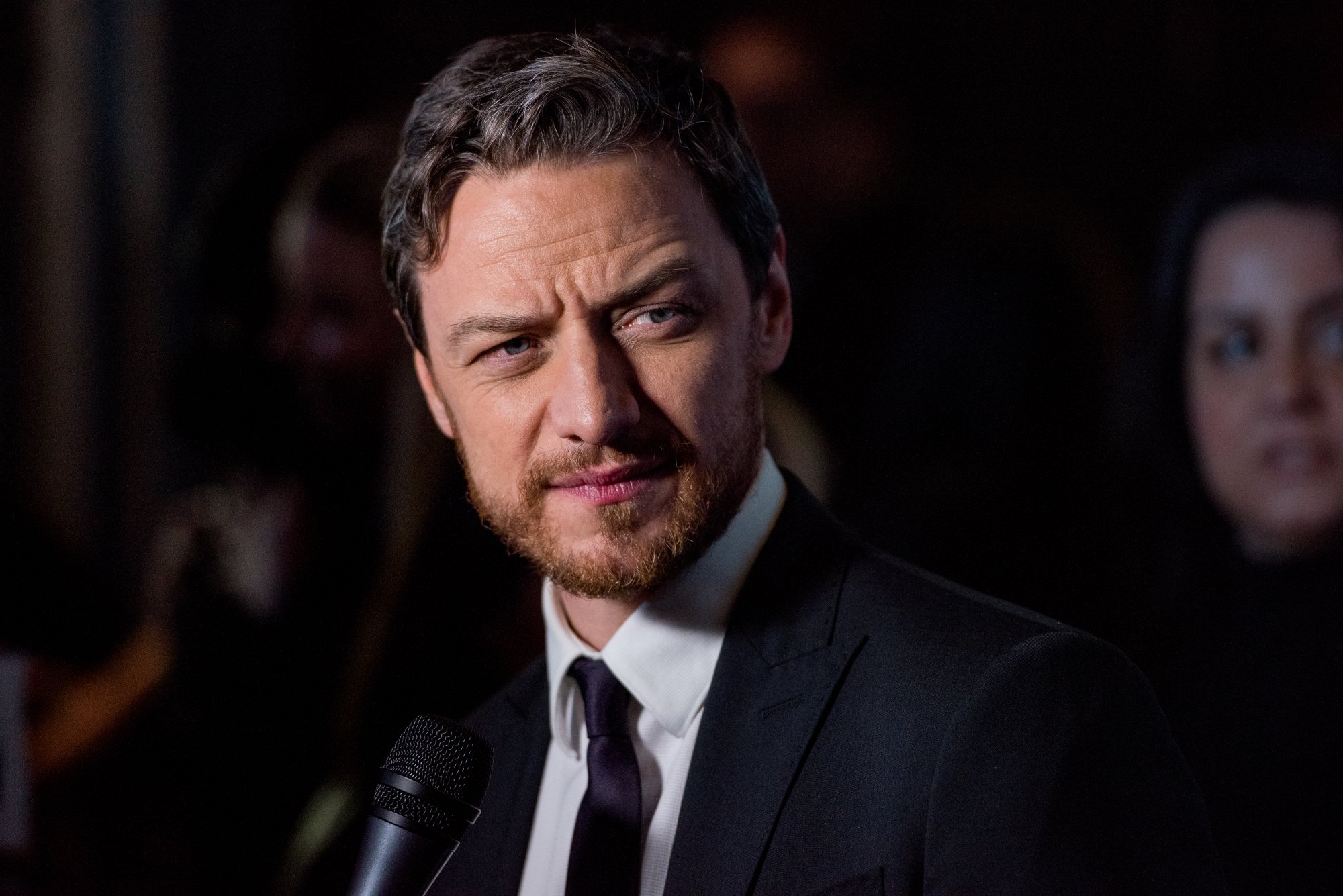 Actor James McAvoy stands in a black suit and tie with a microphone. Before becoming an actor, McAvoy almost led a completely different life as a missionary.