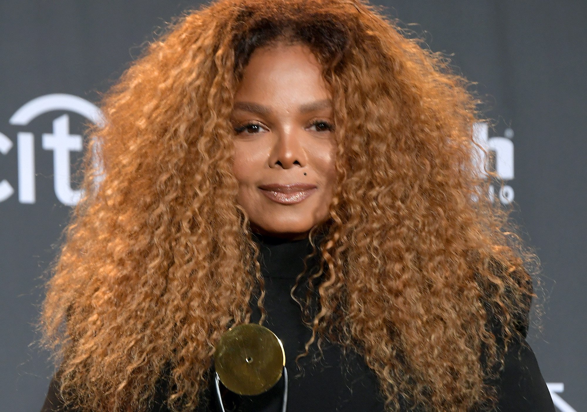 Janet Jackson smiling in front of a black background