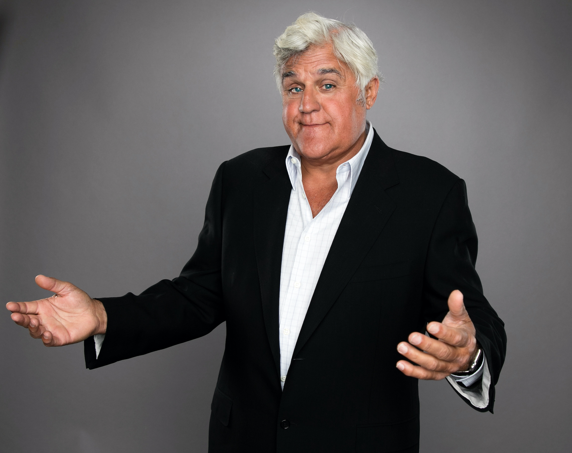 Jay Leno shrugging in front of a gray background