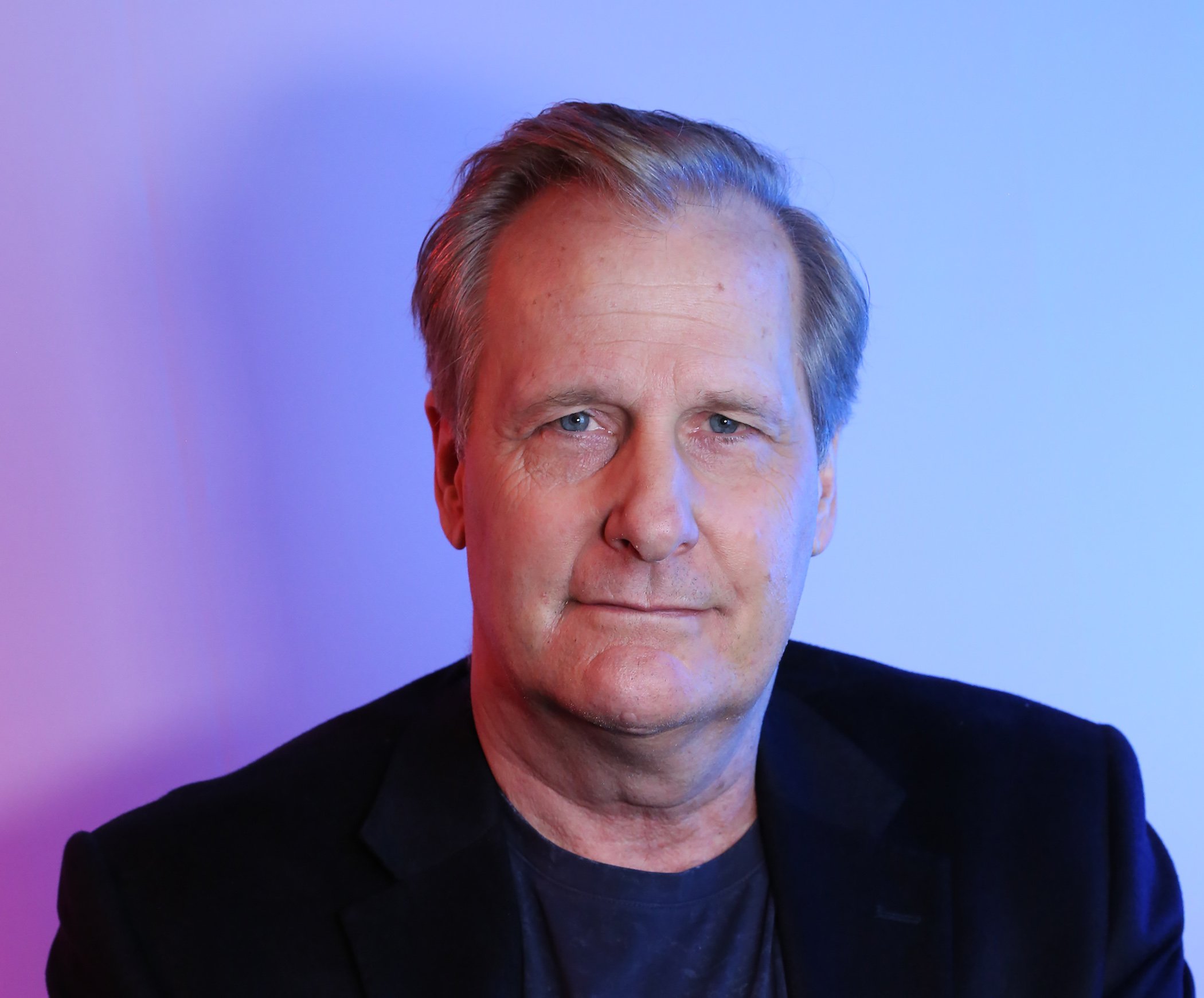 Jeff Daniels of the 'American Rust' cast slightly smiling in a head shot against a blue/purple background