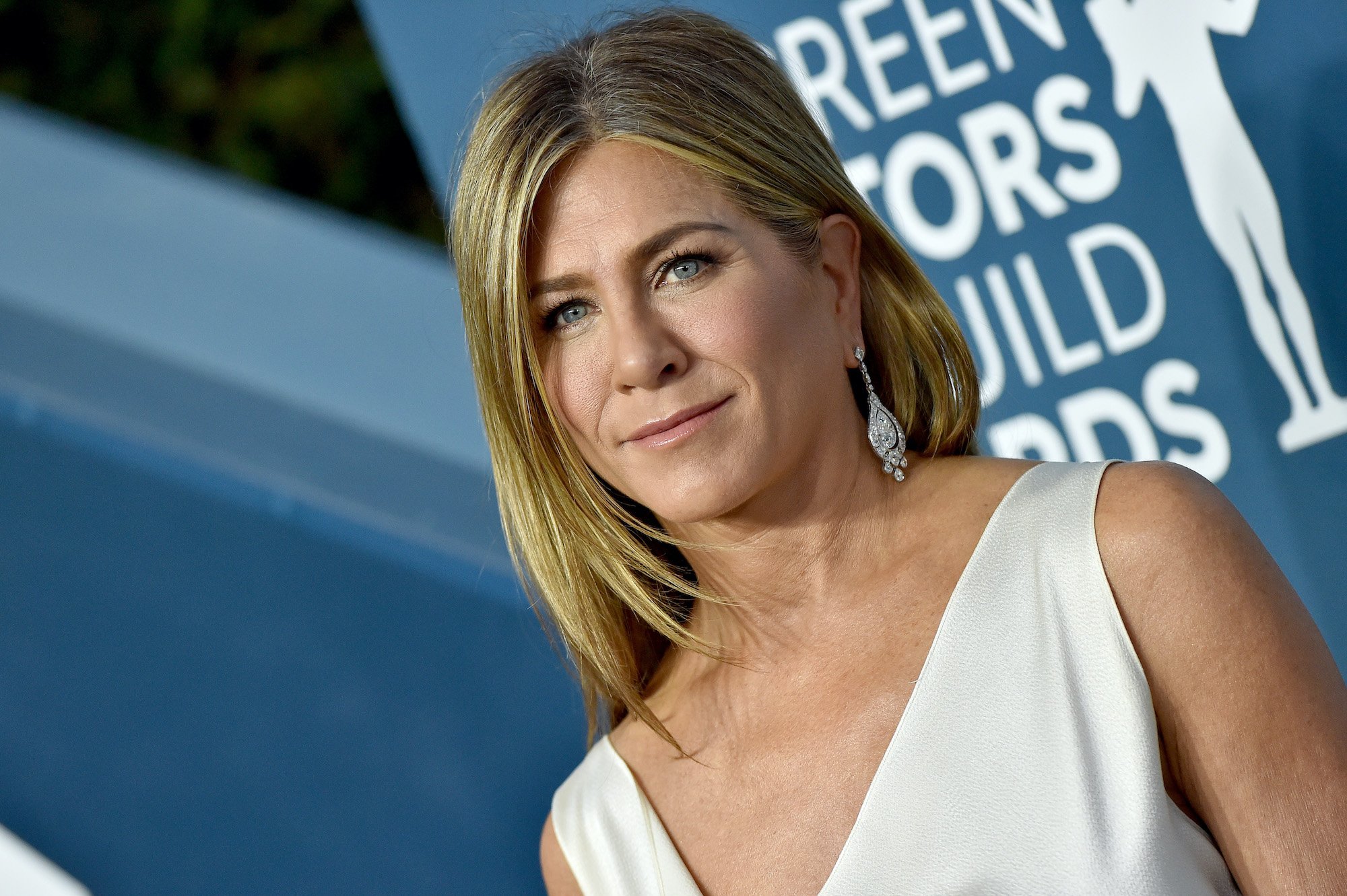 Jennifer Aniston smiling, turned to the side looking at the camera