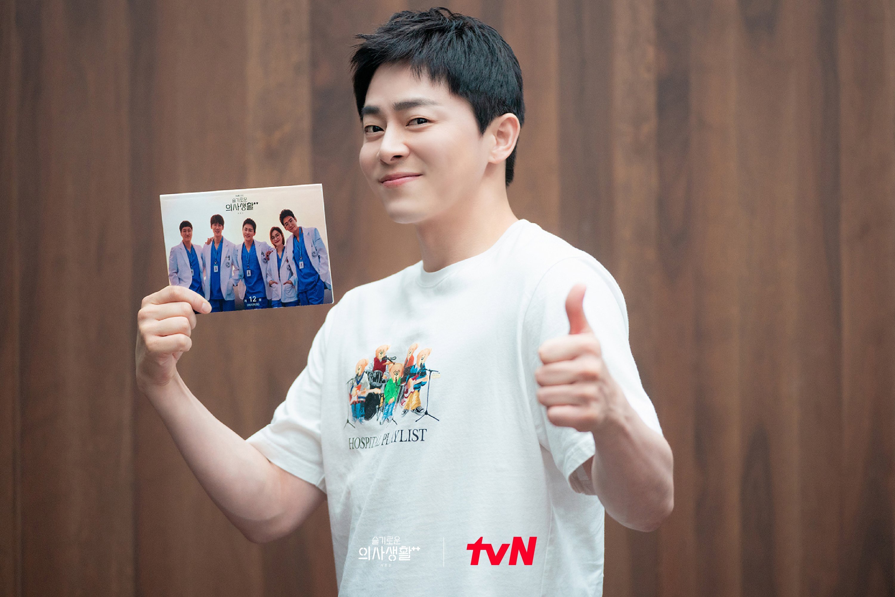 Jo Jung-Suk for 'Hospital Playlist' Netflix K-drama wearing white shirt and holding cast photo 