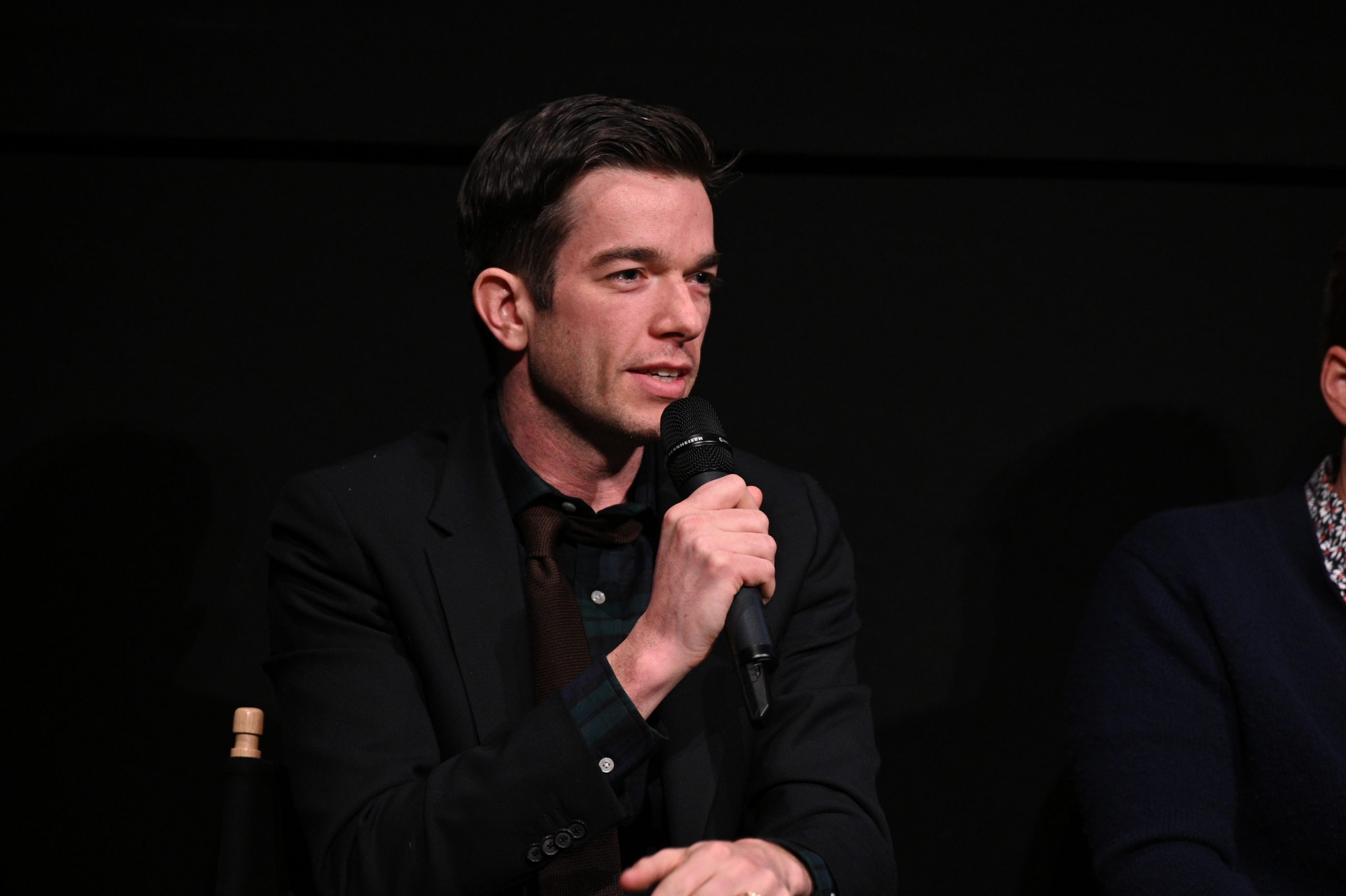 Comedian John Mulaney holds a microphone