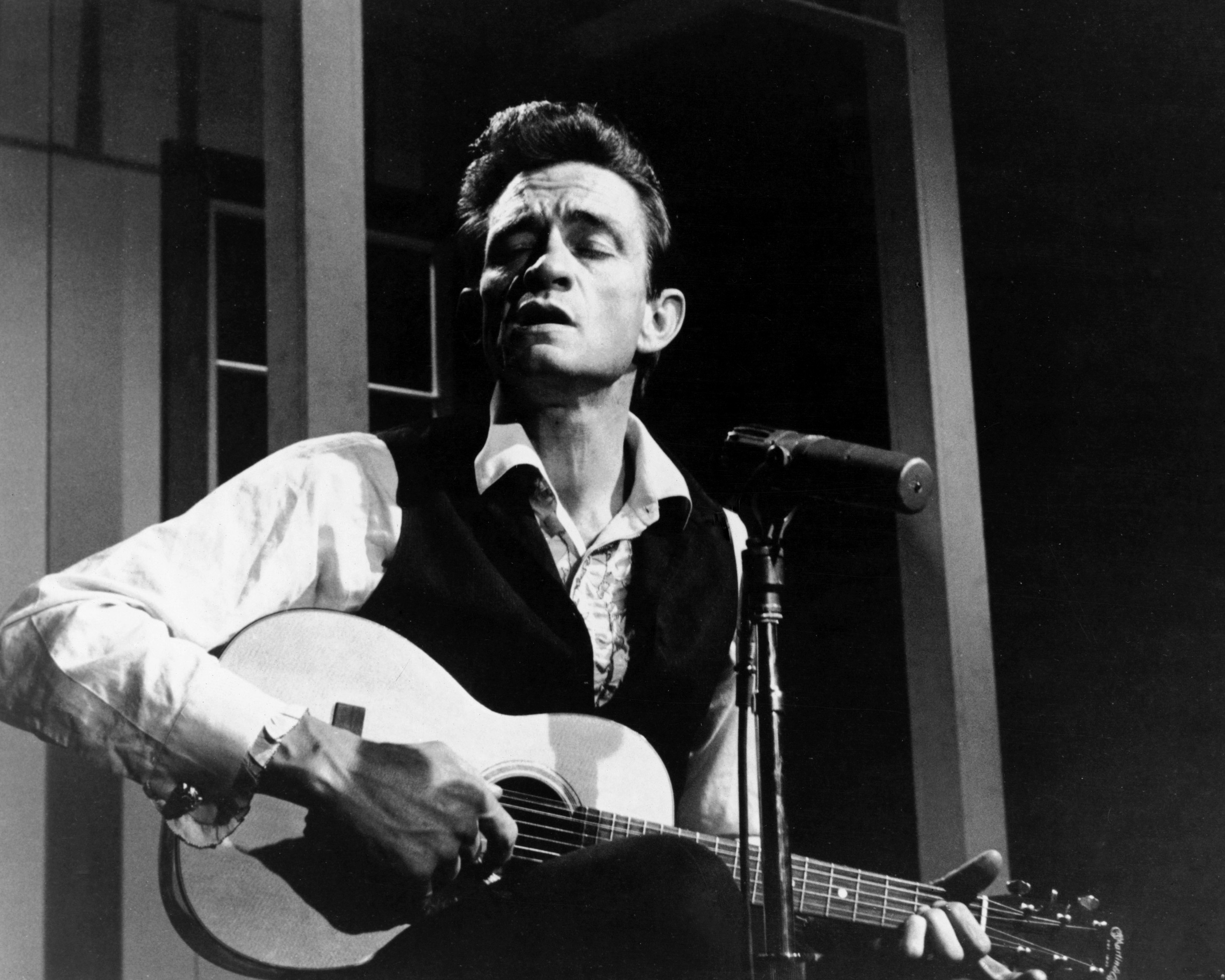 Johnny Cash performs a song with his guitar.