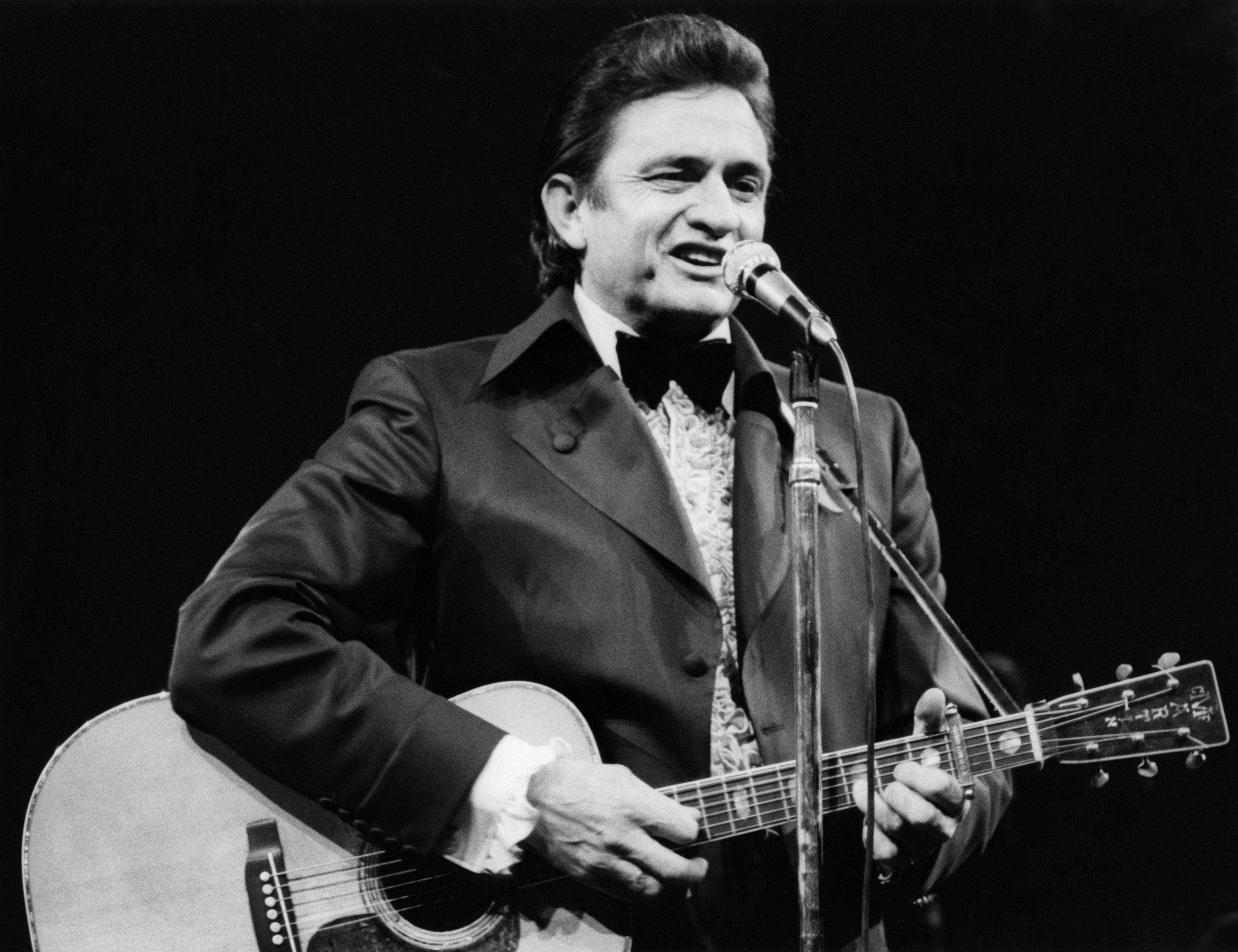 Johnny Cash plays guitar and sings onstage.