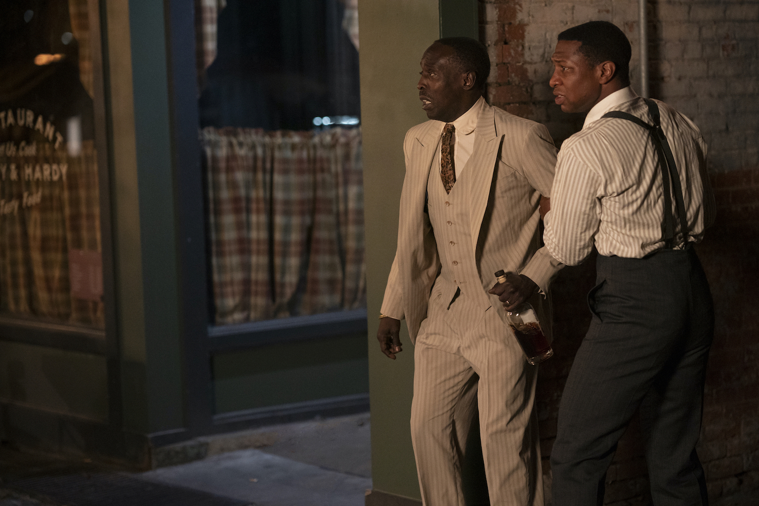 Jonathan Majors holds Michael K. Williams' arm in Lovecraft Country